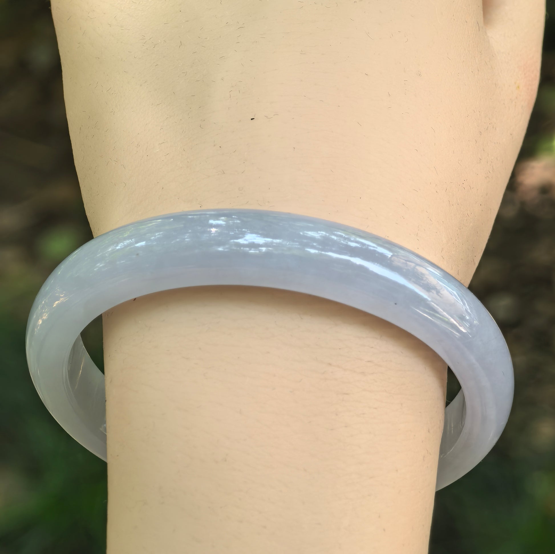 Close-up of a Natural Grade-A icy glutinous blue-lavender jadeite oval bangle worn on the wrist.