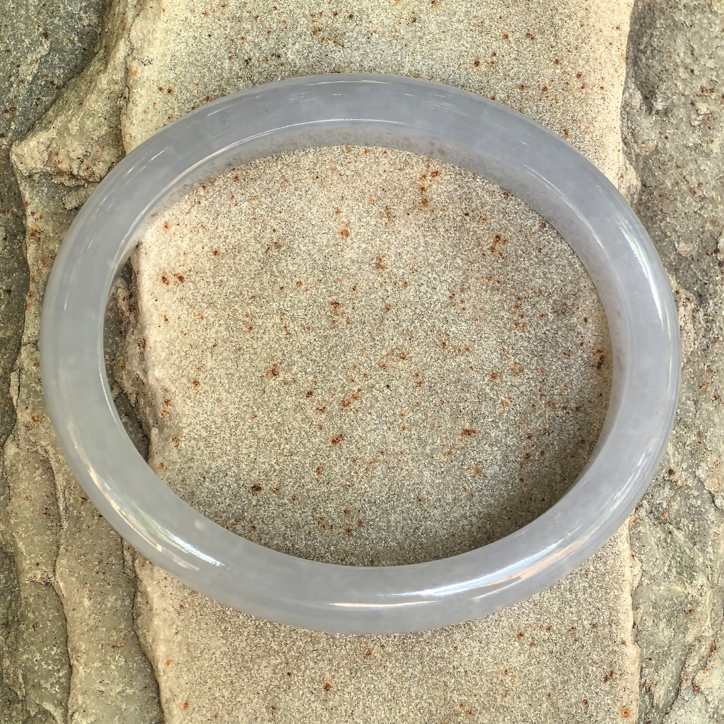 Top view of an icy glutinous blue-lavender jadeite oval bangle showing its natural color and internal texture.