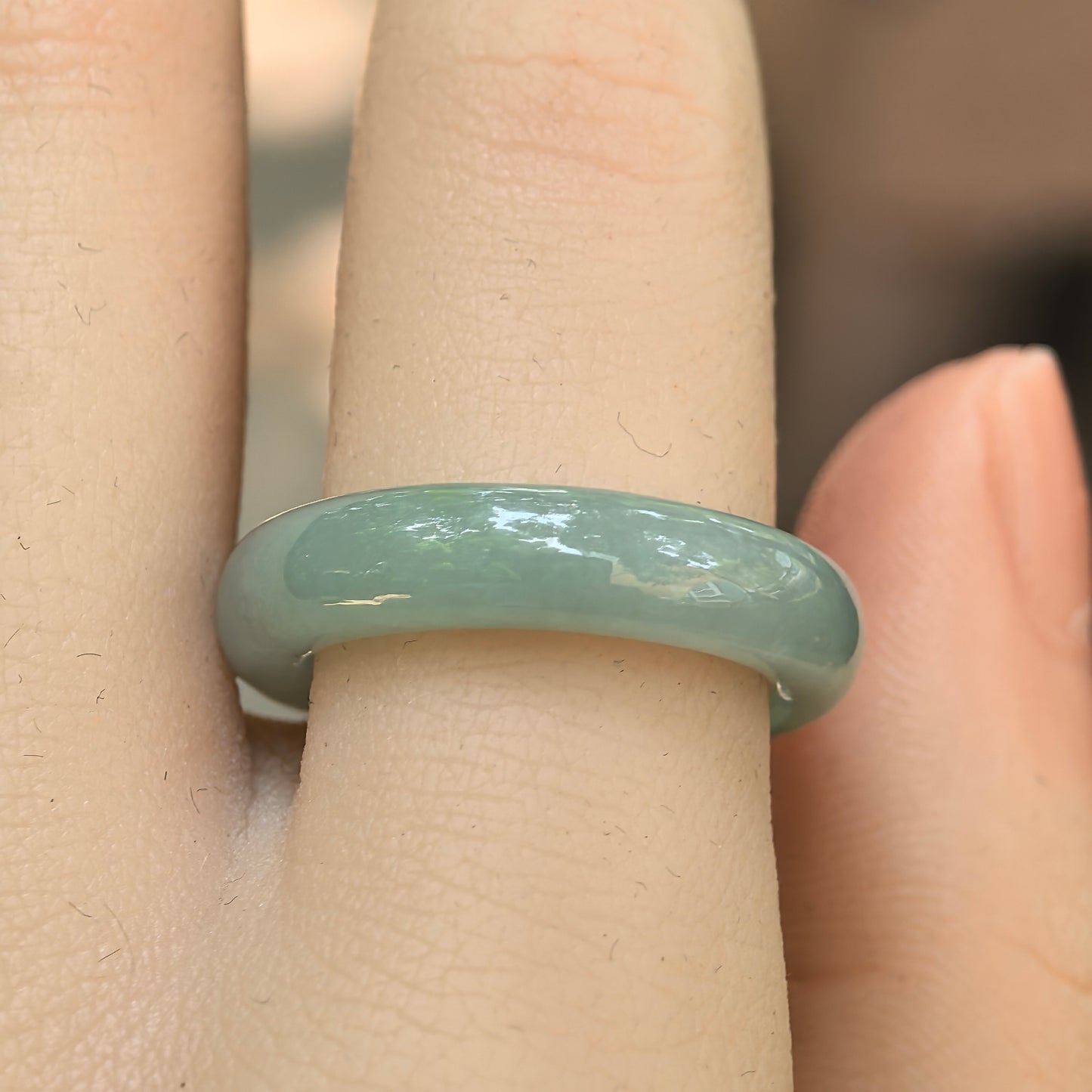 Close-up wearing view of the light green Burmese jadeite ring with good translucency and natural luster.