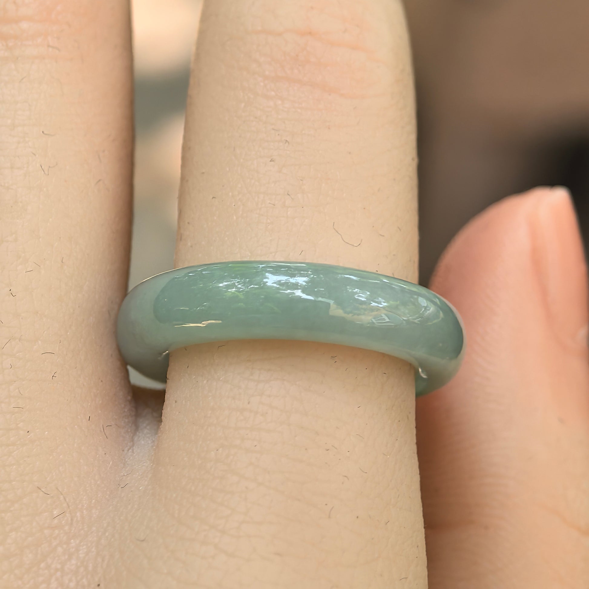 Close-up wearing view of the light green Burmese jadeite ring with good translucency and natural luster.