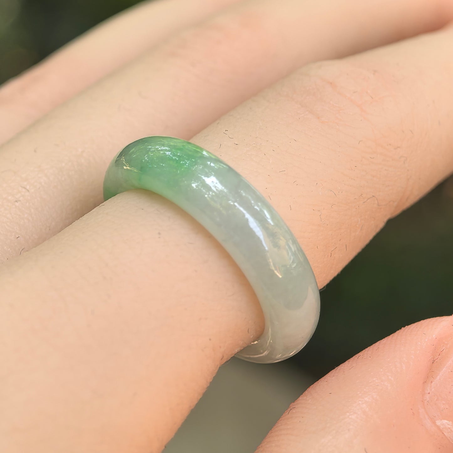 NGTC-certified icy glutinous light green jadeite ring band worn on a finger, showing its rounded profile and polished luster.