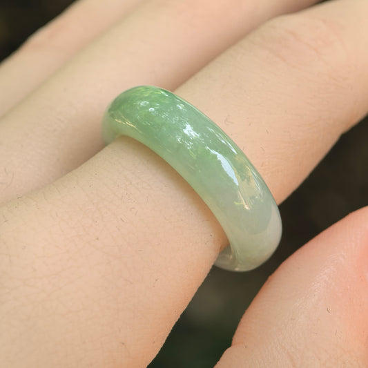 NGTC-certified icy glutinous light green jadeite ring band worn on a finger, showing its thick rounded profile and polished luster.