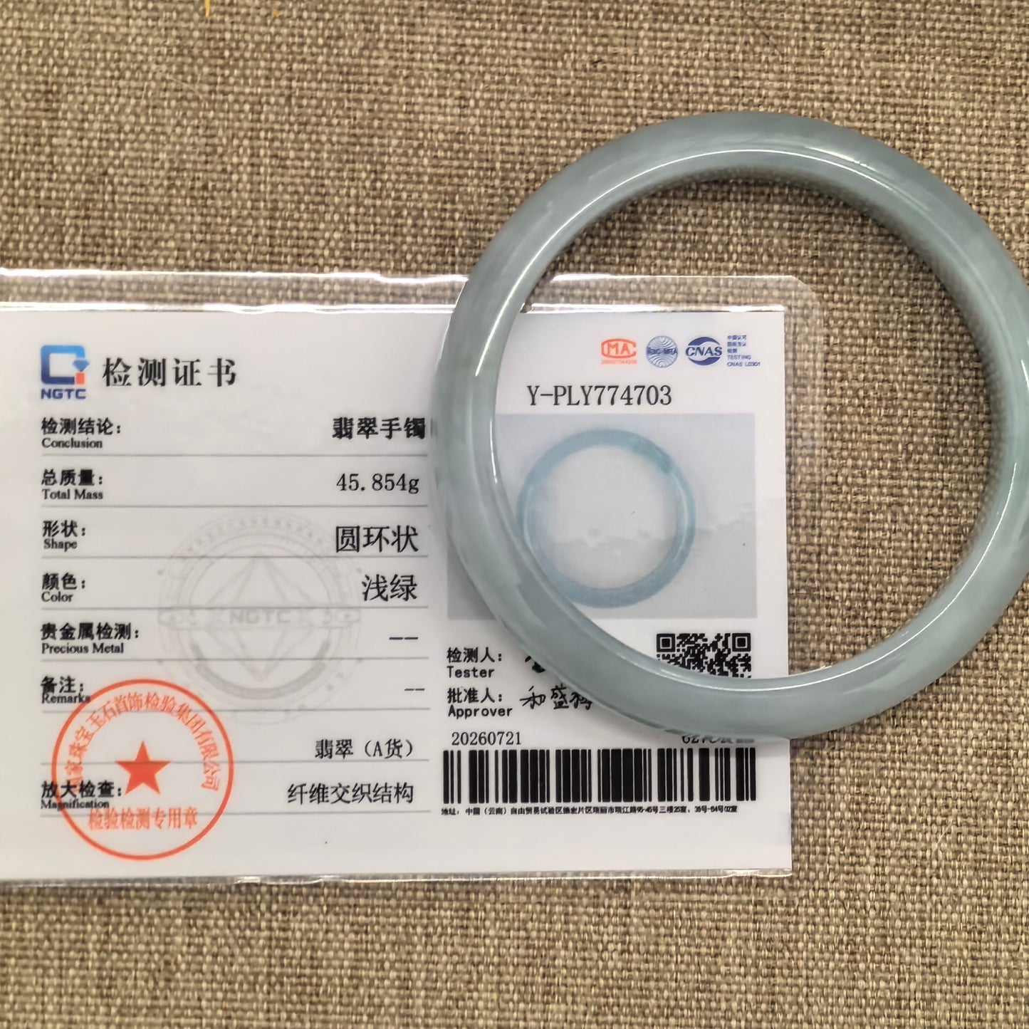 NGTC-certified light green Burmese jadeite bangle displayed with its matching authentication certificate.