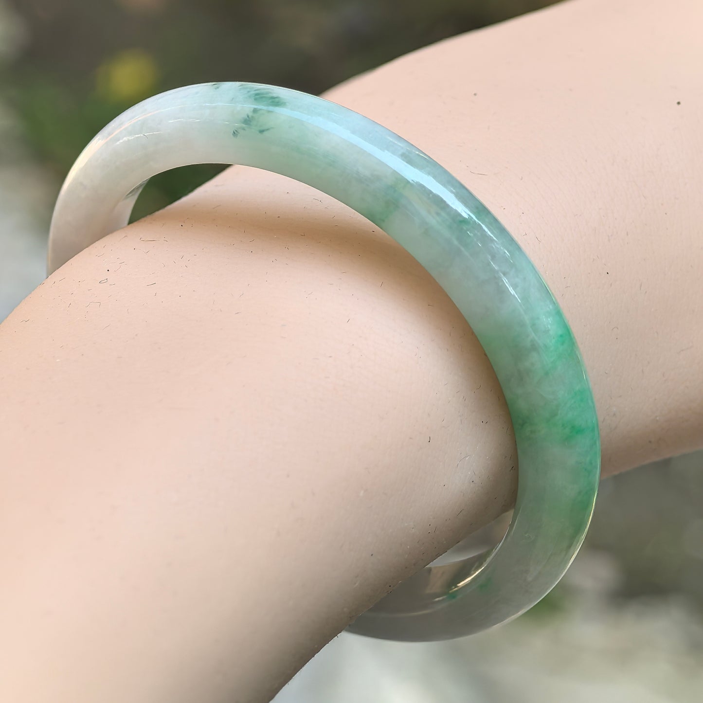 Natural Grade-A glutinous white-base green D-shape jadeite bangle worn on the wrist.