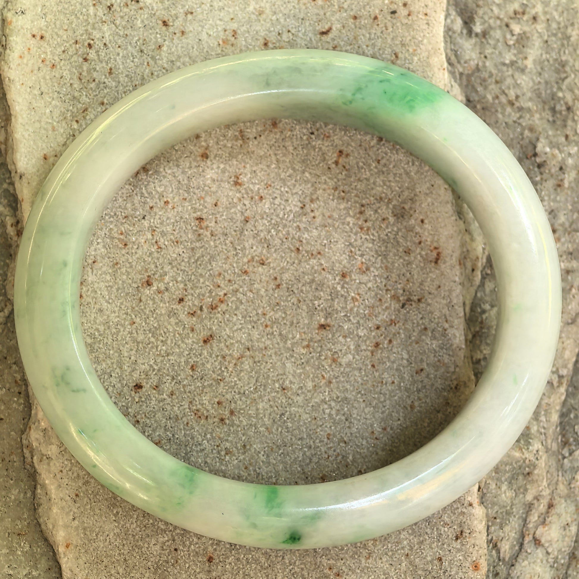 Top view of the natural Grade-A white-base green oval jadeite bangle showing its polished oval structure.