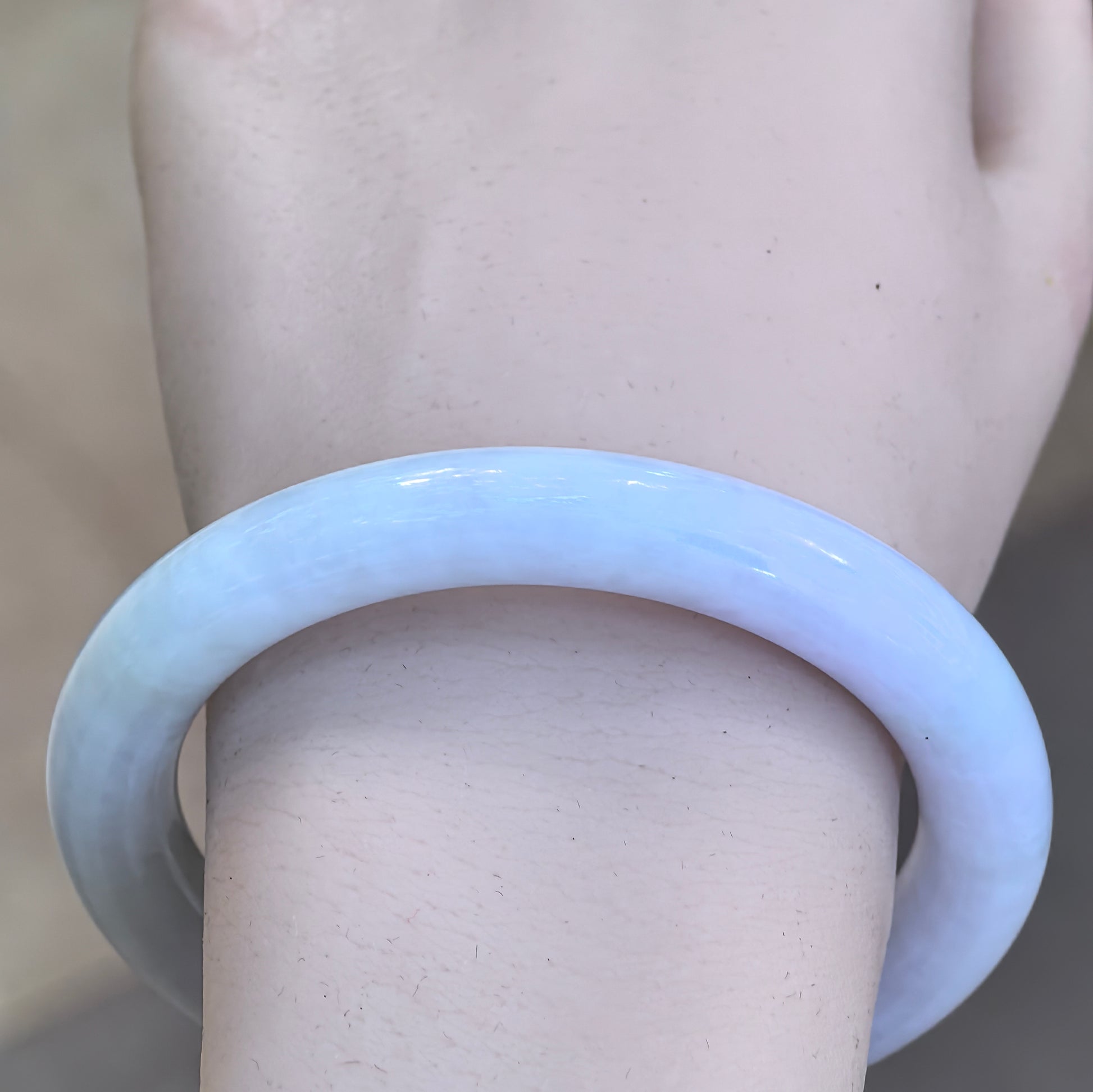 Wrist view of the very pale spring-color Burmese jadeite bangle showing its smooth round-bar profile.