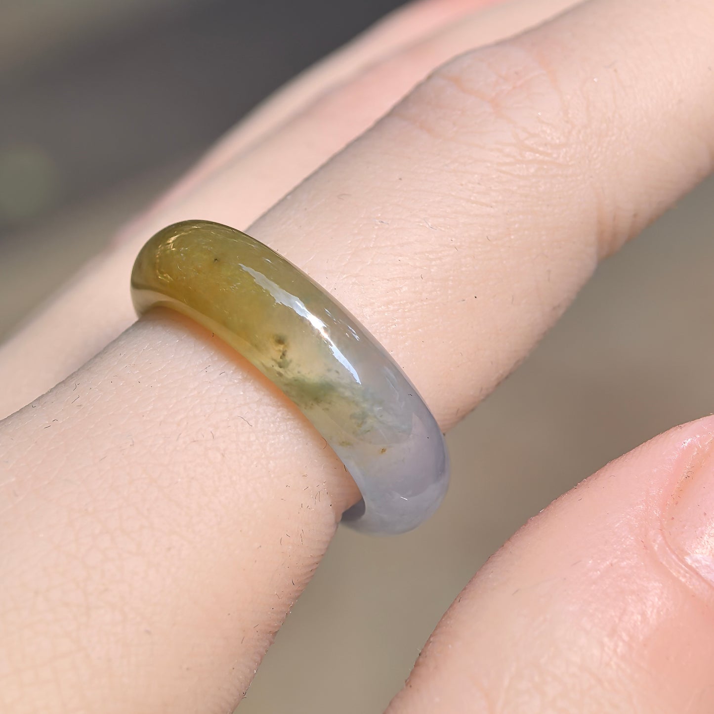 Natural Grade-A icy glutinous half-yellow jadeite ring band worn on a finger, showing its brownish-yellow and pale green color transition.