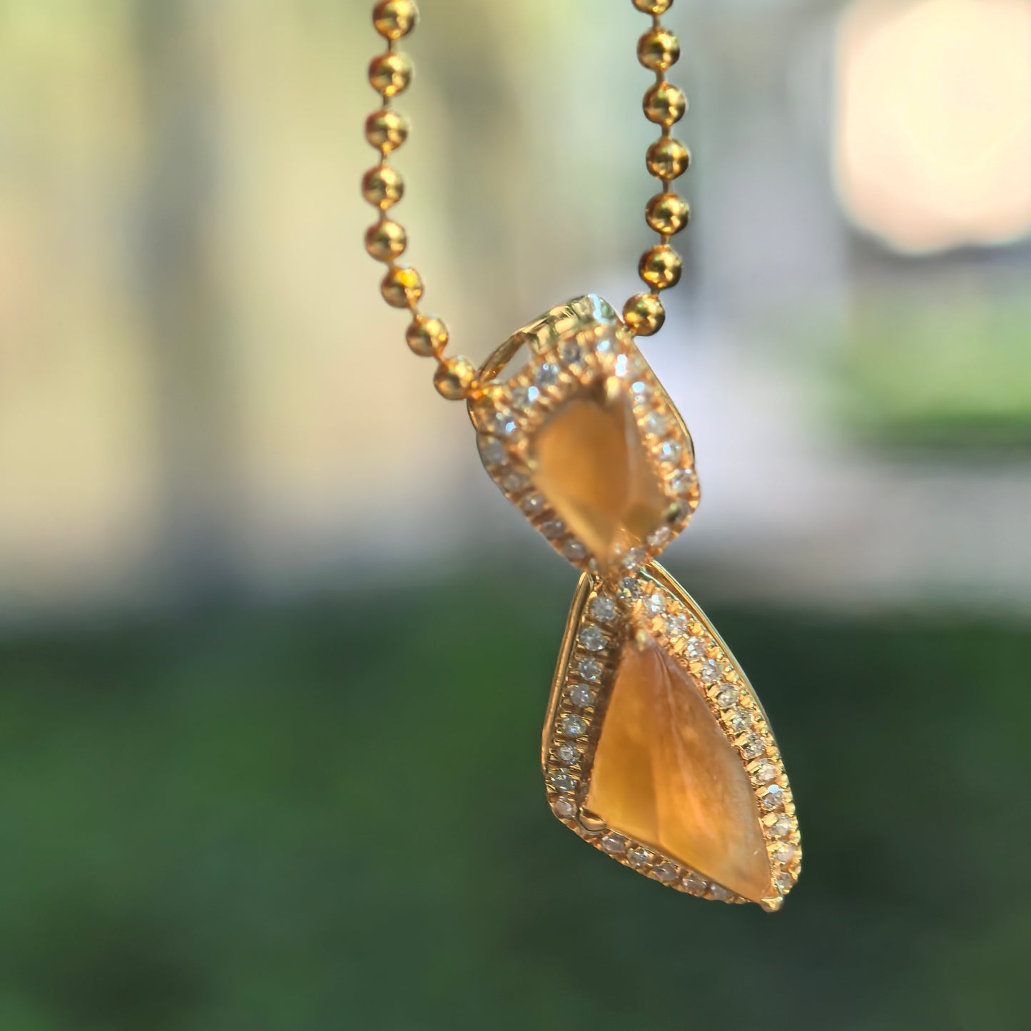 Natural Grade-A icy golden yellow freeform jadeite pendant in 18K gold with diamond accents hanging from a chain.