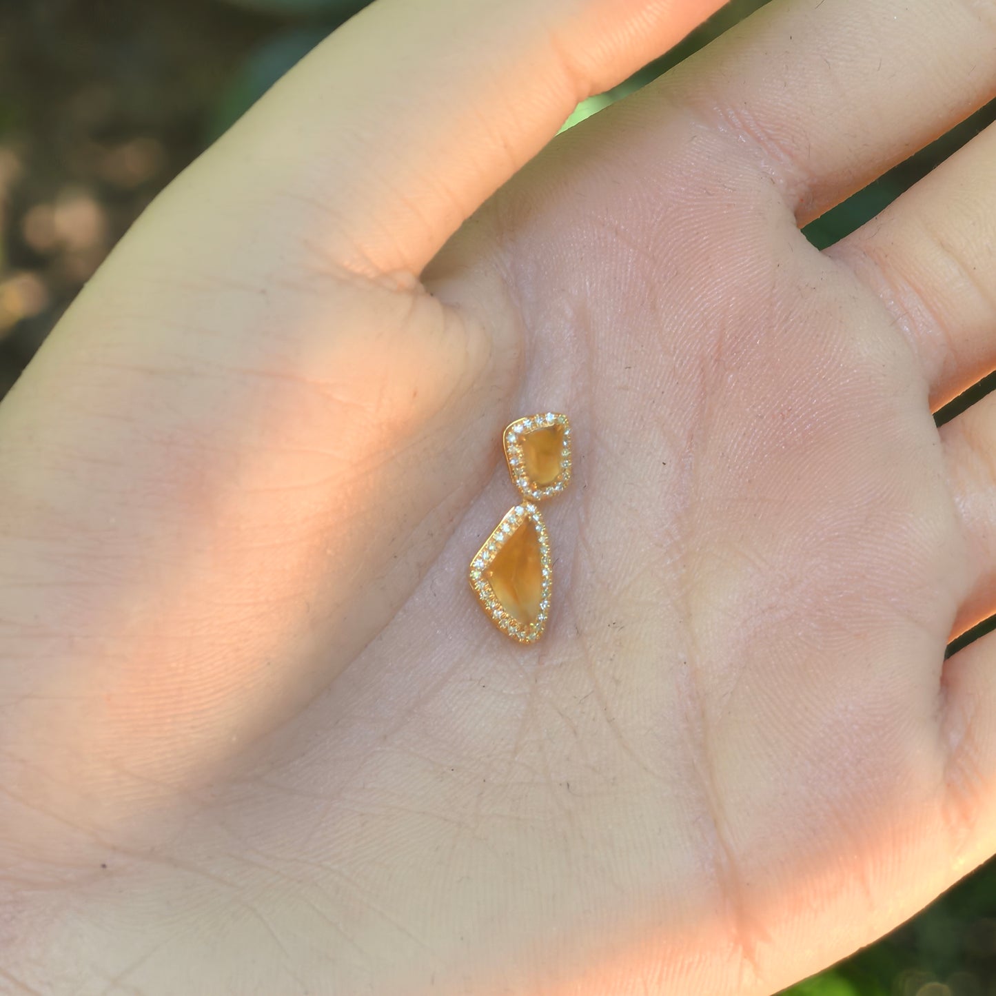 Hand-held view of the petite golden yellow jadeite pendant showing its two-piece articulated drop design.