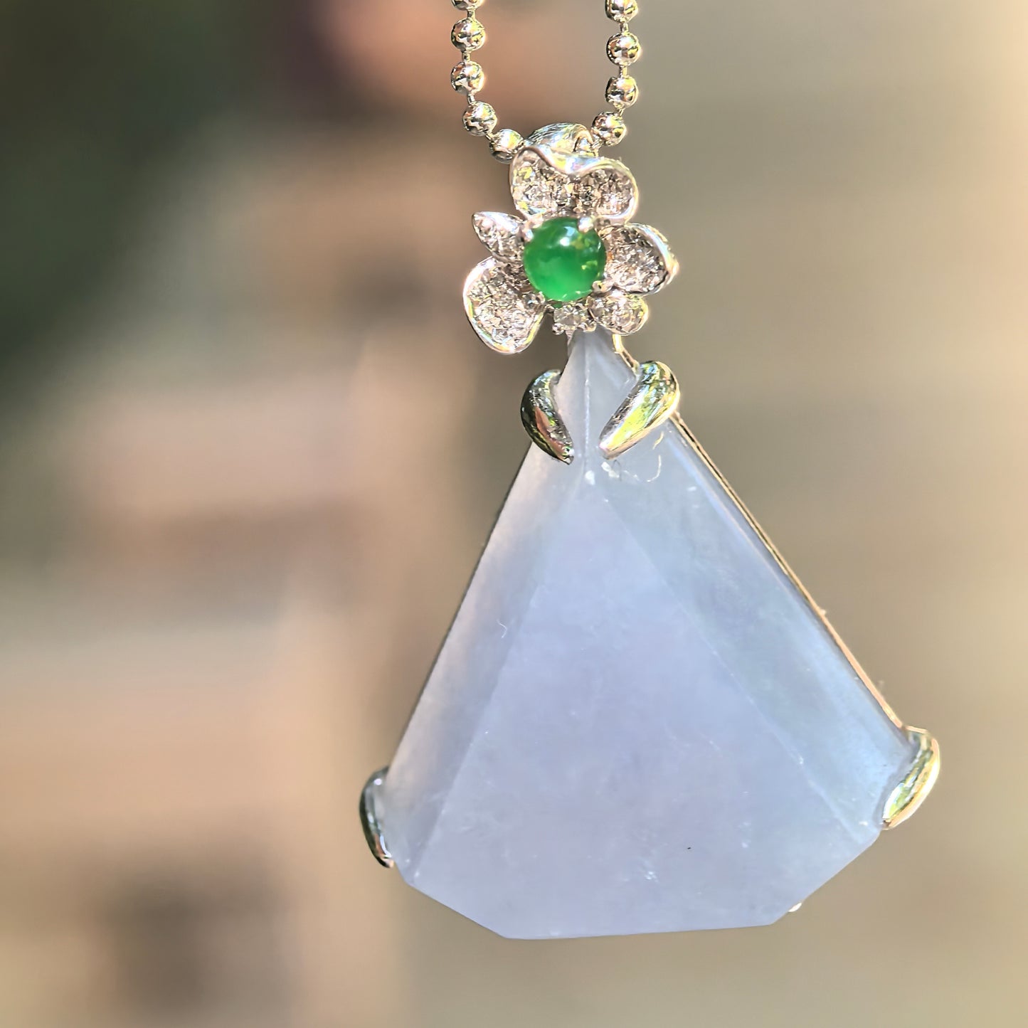Natural Grade-A icy glutinous lavender triangular jadeite pendant with an 18K white gold floral bail, diamonds, and green jadeite accent.