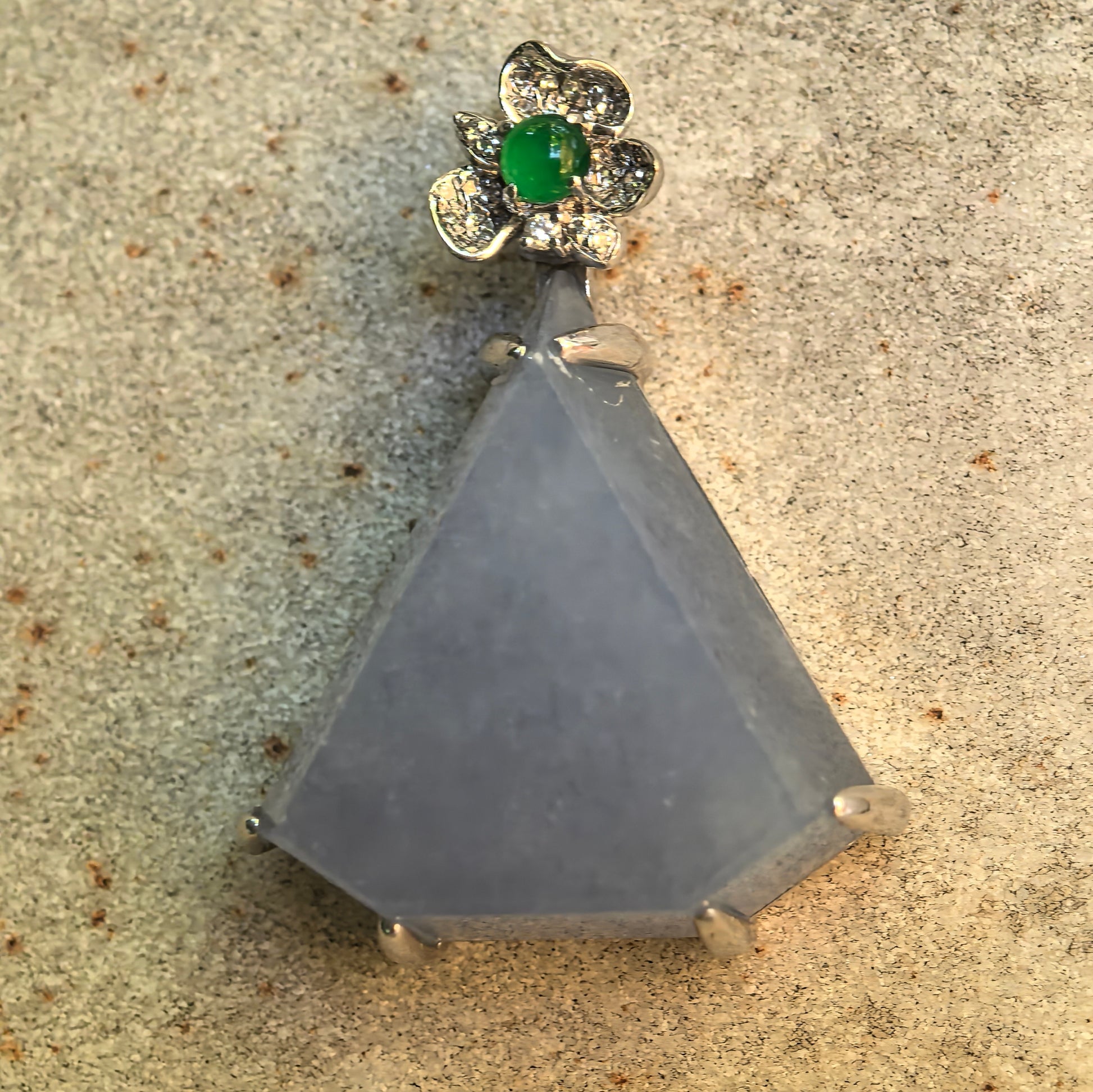 Close-up of the 18K white gold flower bail with diamond accents and a vivid green jadeite cabochon above the lavender pendant.