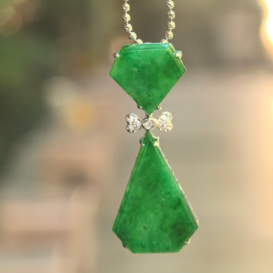 Natural Grade-A icy glutinous rich green bow-tie jadeite pendant hanging from a chain with an articulated geometric design.