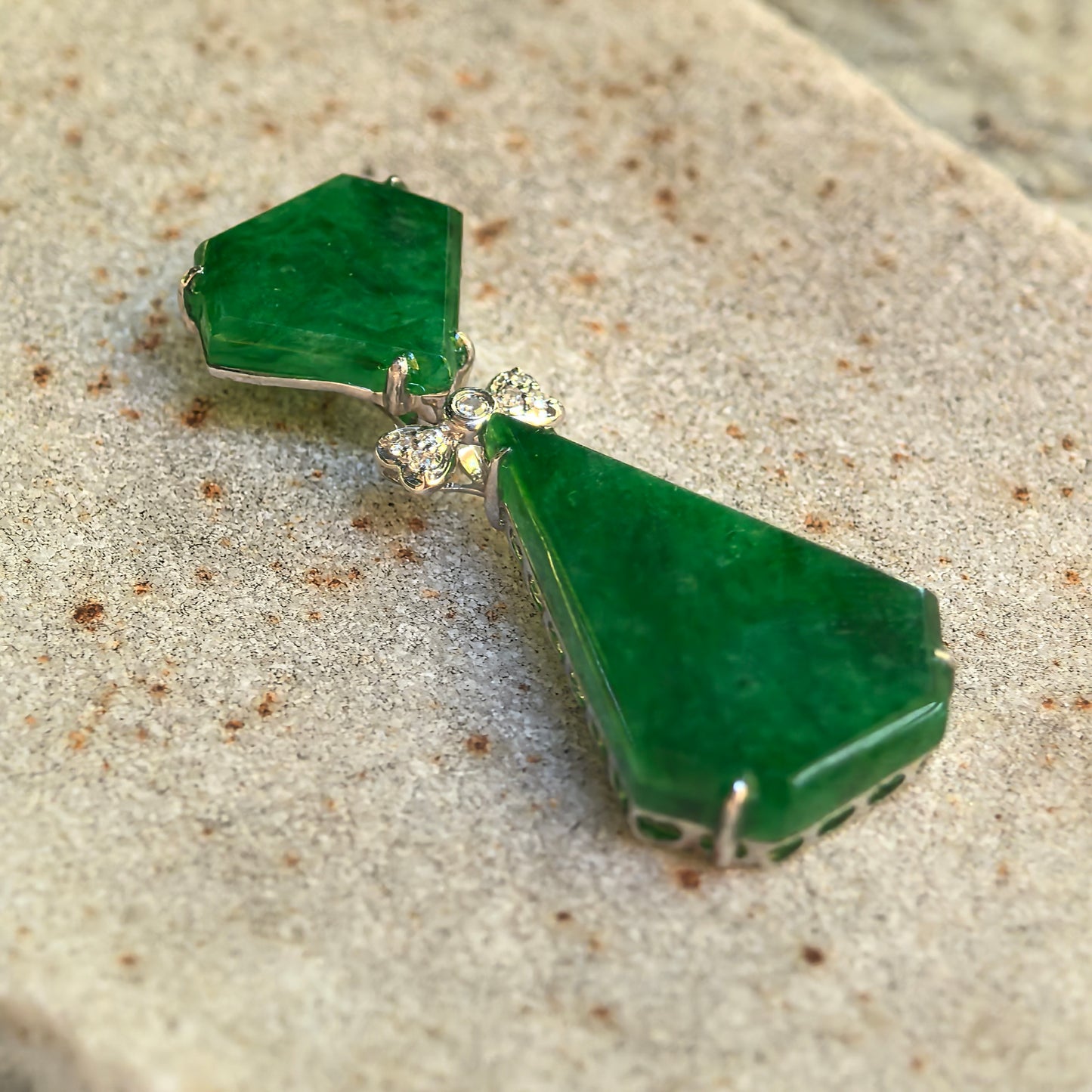 Close-up of the icy glutinous green jadeite pendant showing its polished facets, 18K gold prongs, and bow-shaped connector.