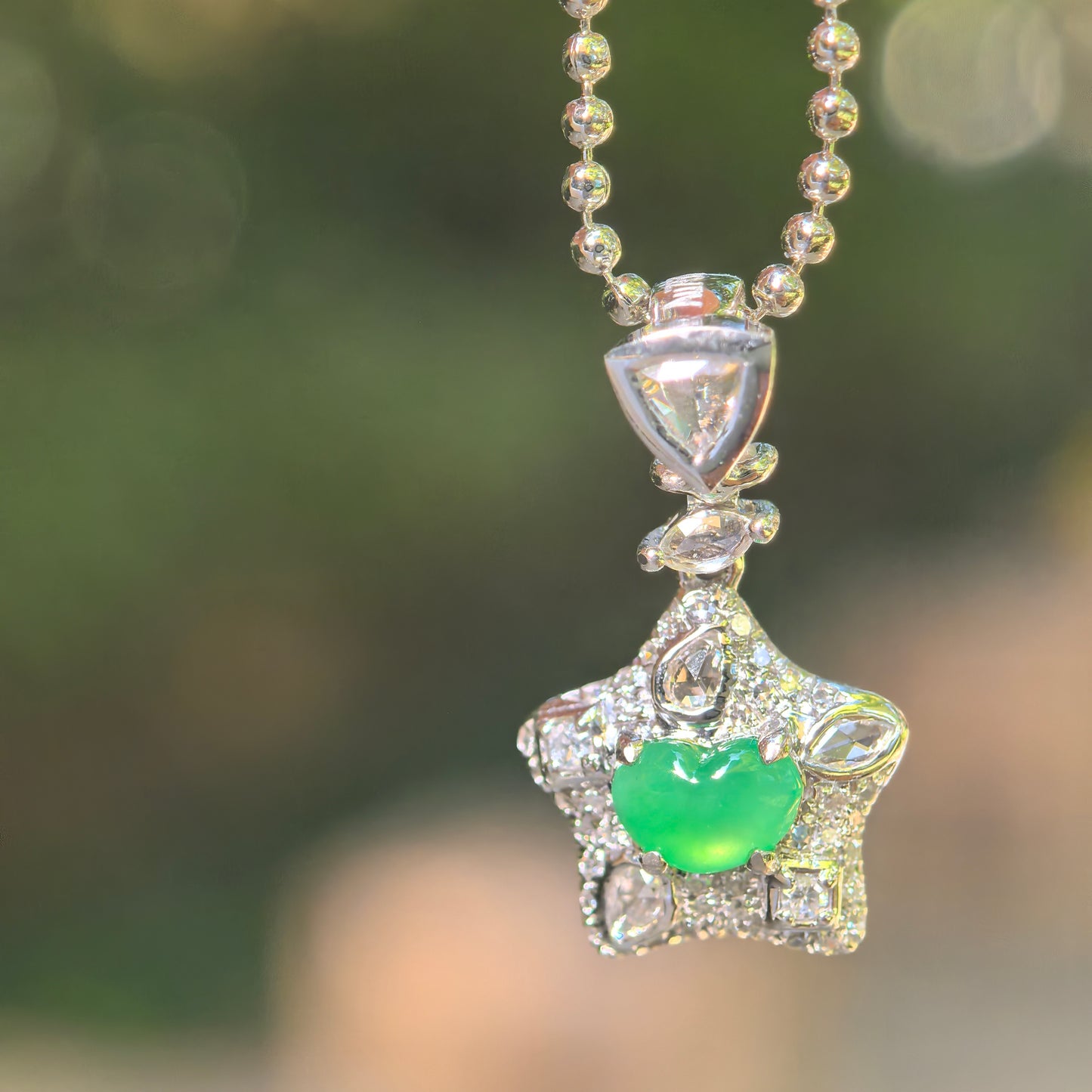 Natural Grade-A icy vivid green heart jadeite pendant in a diamond-set 18K gold star design hanging from a chain.
