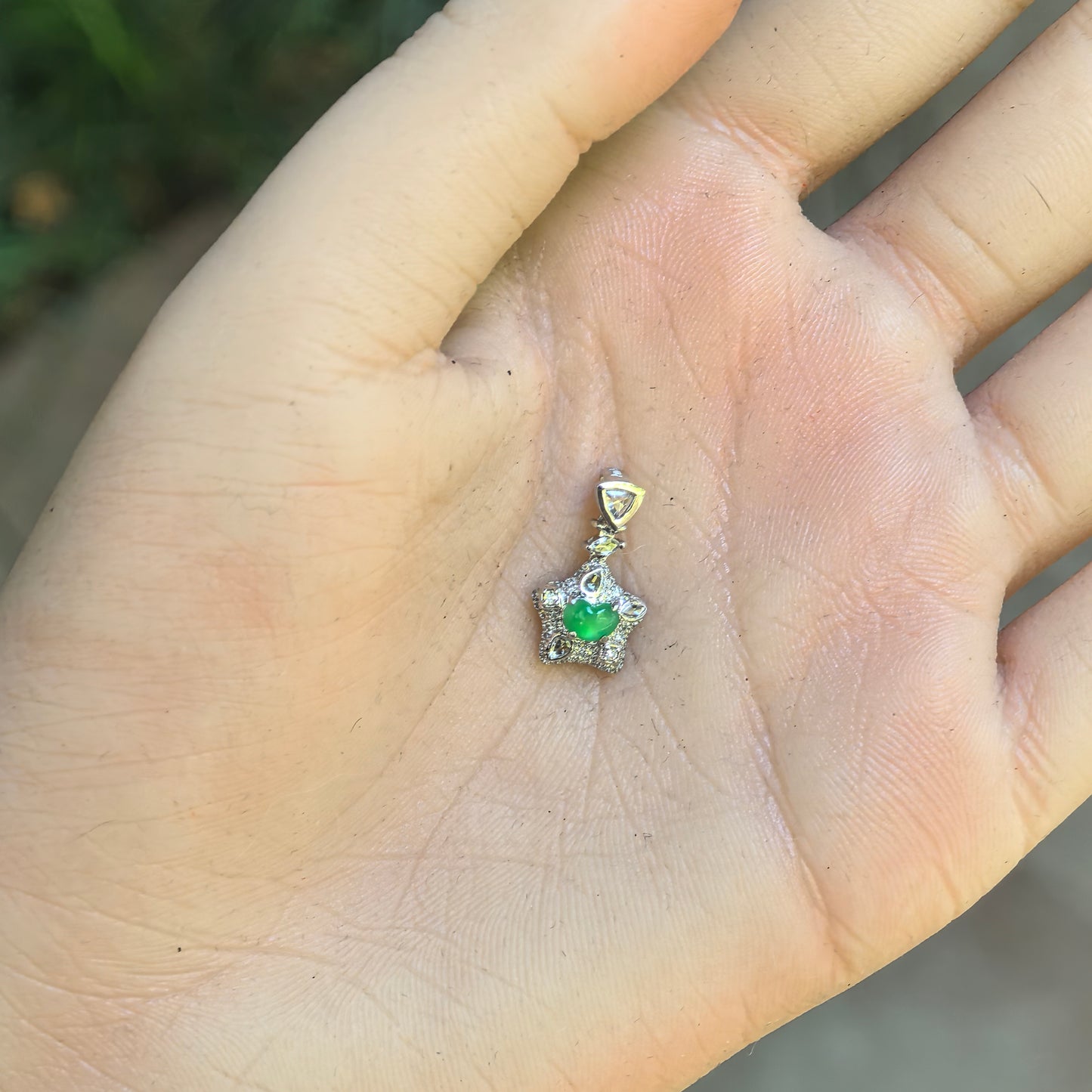 Hand-held view of the petite green heart jadeite pendant showing its 18K gold setting and overall proportions.