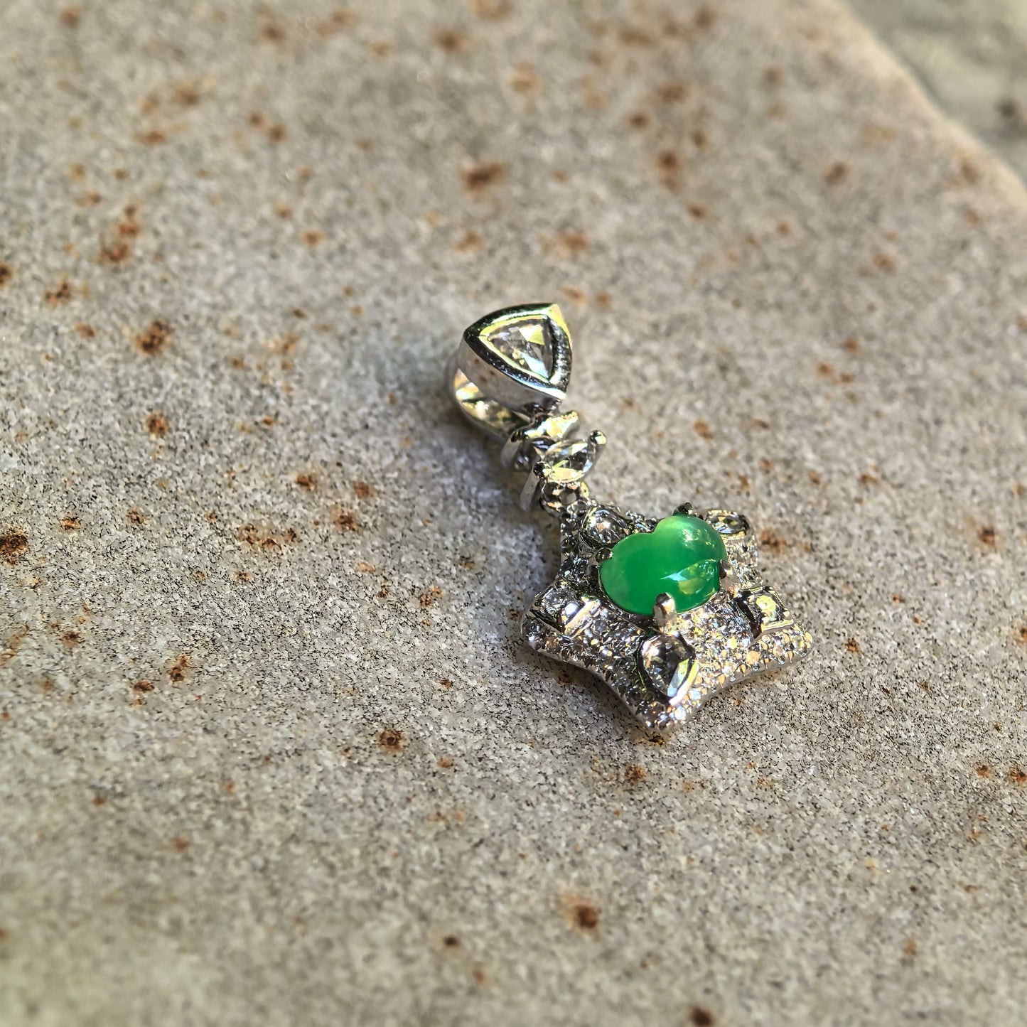 Angled detail view of the icy green jadeite pendant showing the articulated bail, diamond accents, and raised 18K gold structure.