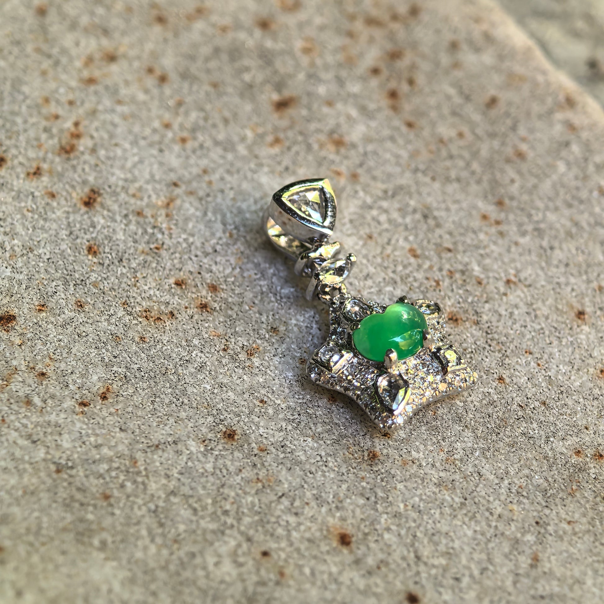 Angled detail view of the icy green jadeite pendant showing the articulated bail, diamond accents, and raised 18K gold structure.