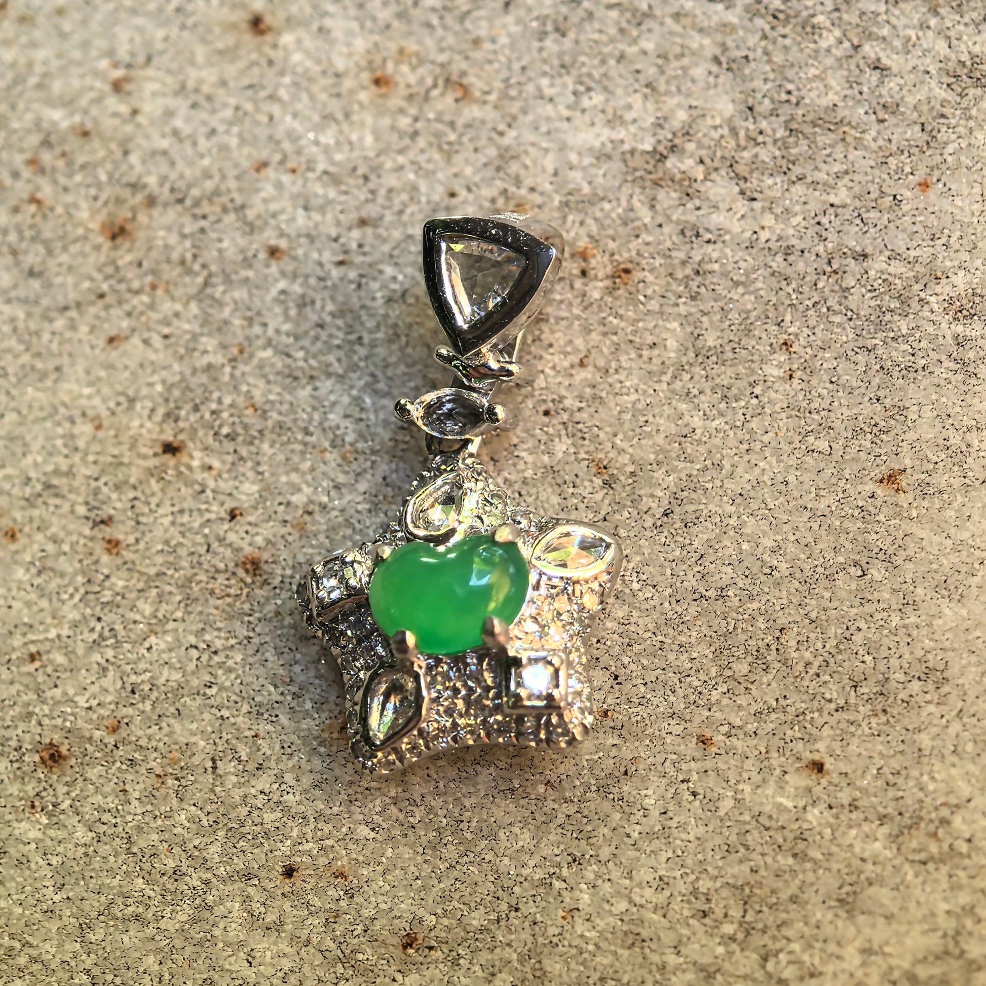 Close-up of the vivid green heart-shaped jadeite cabochon surrounded by faceted diamonds in a star-shaped setting.