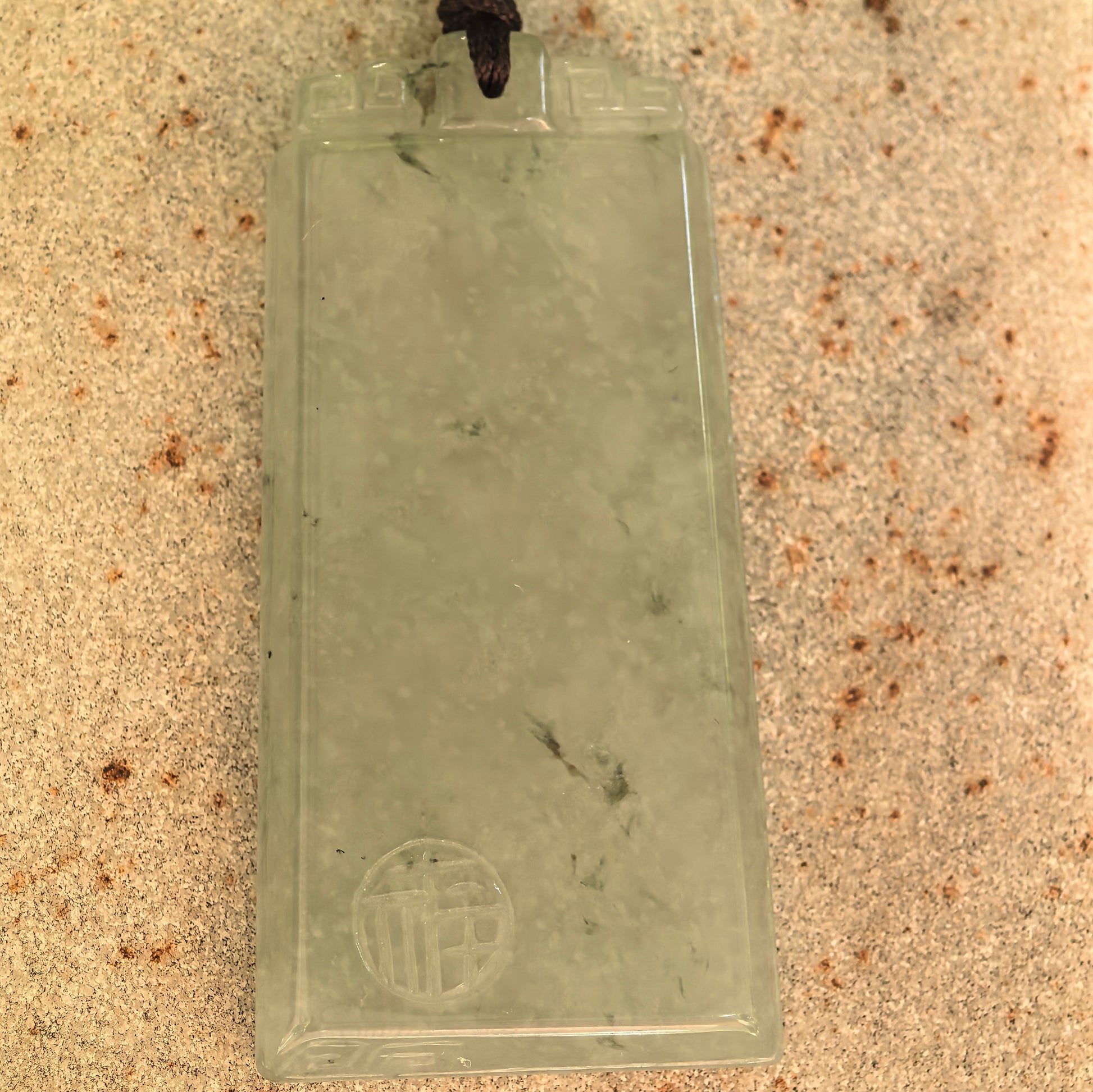 Front view of the icy glutinous light green jadeite plaque pendant showing its clean rectangular surface and decorative top.