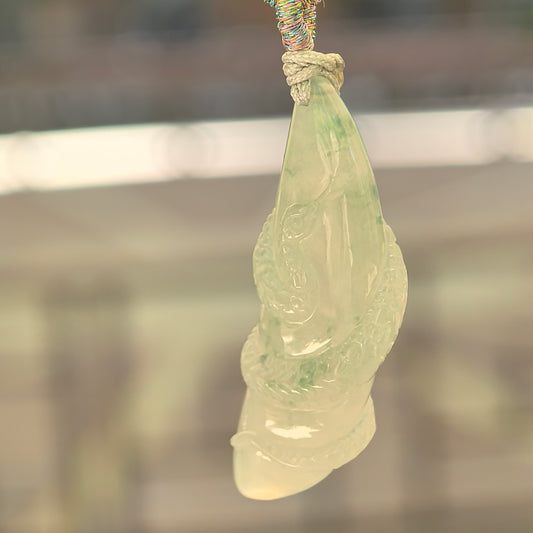 Natural Grade-A icy glutinous light green snake jadeite pendant hanging from its woven cord in natural light.