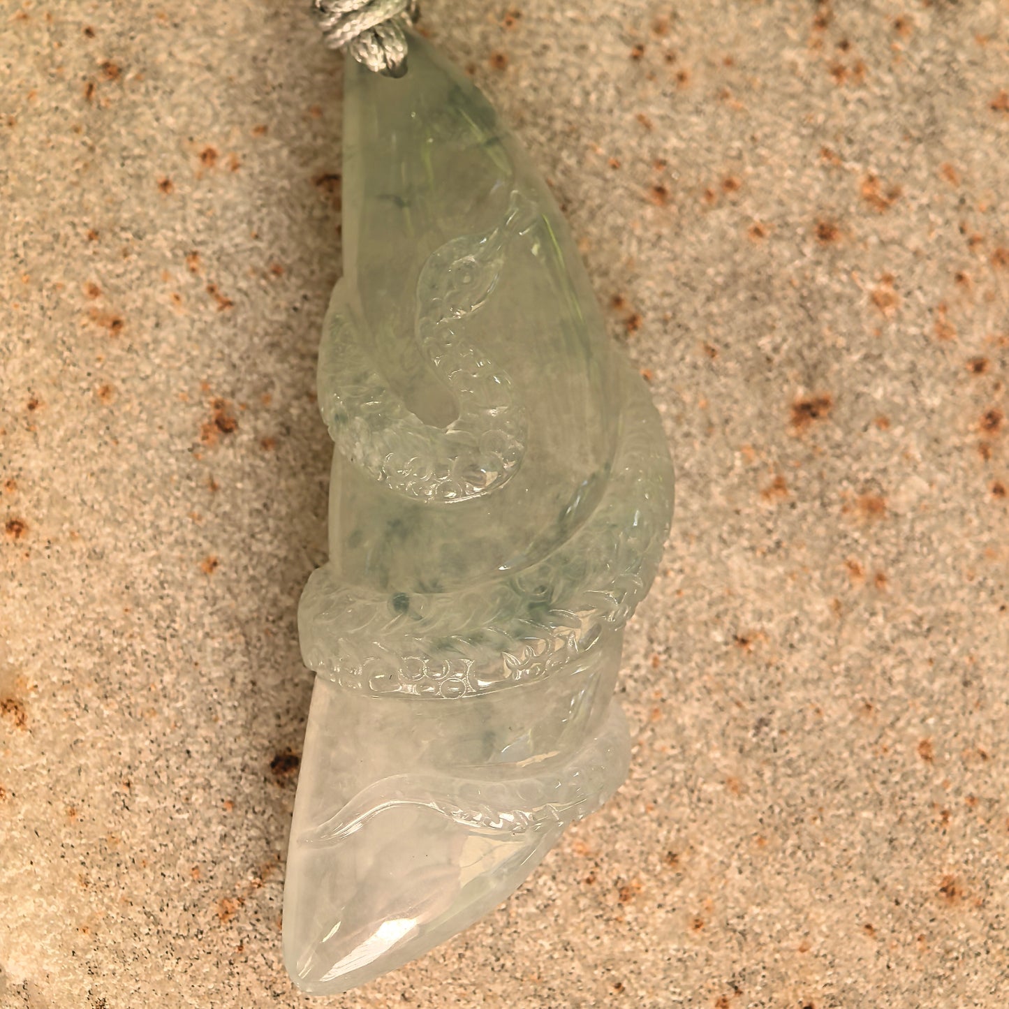 Close-up of the icy glutinous jadeite snake pendant showing the raised carving, scale details, and smooth glassy luster.