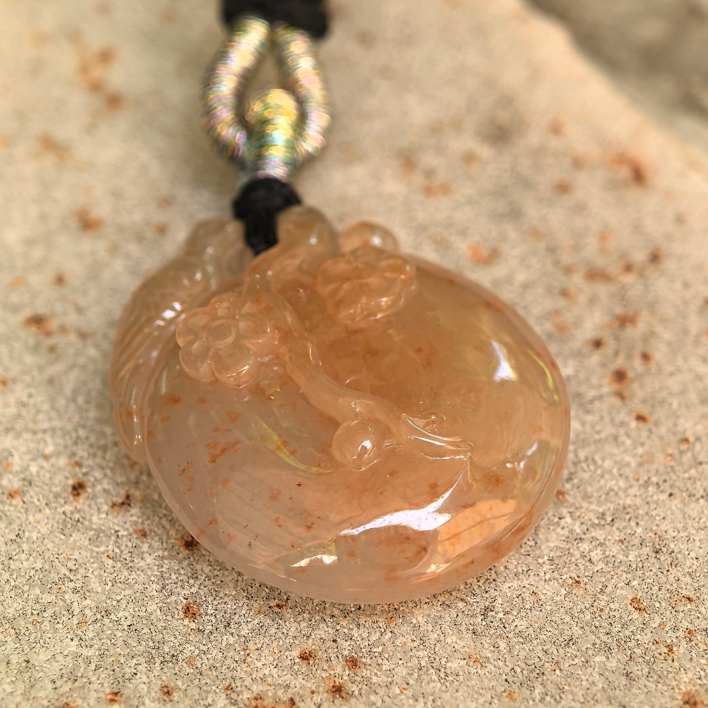 Angled close-up of the round yellow Burmese jadeite pendant showing its domed form, natural brown speckling, and smooth luster.