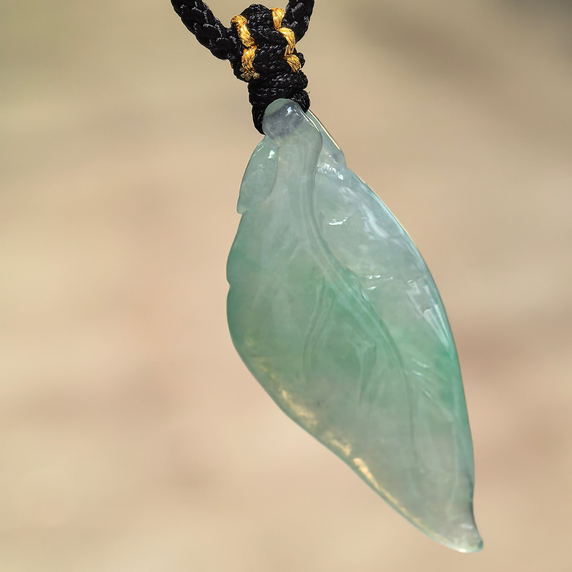 Natural Grade-A icy glutinous light green leaf jadeite pendant hanging from its black woven cord.