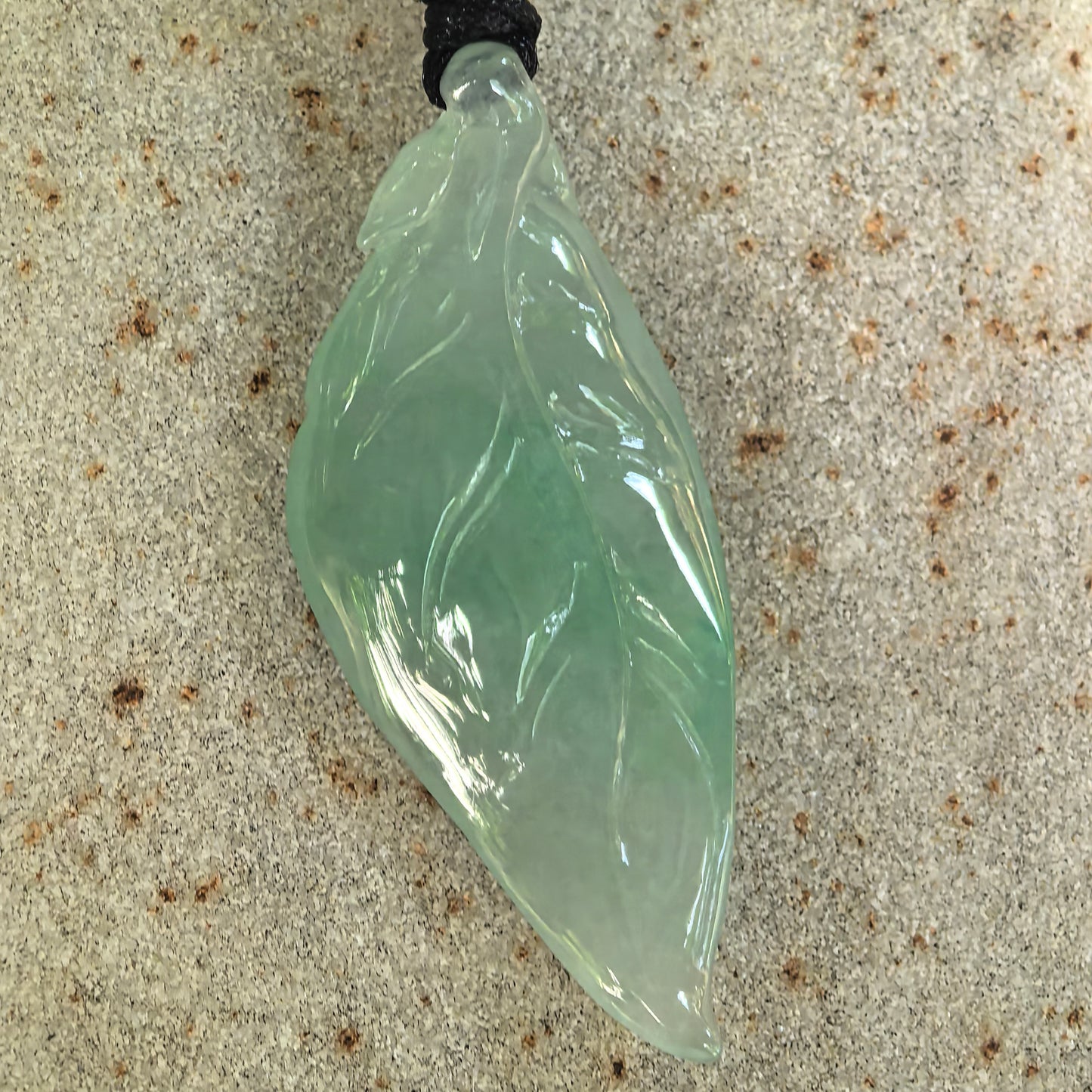 Front detail of the light green leaf jadeite pendant showing the softly curved profile and polished natural surface.