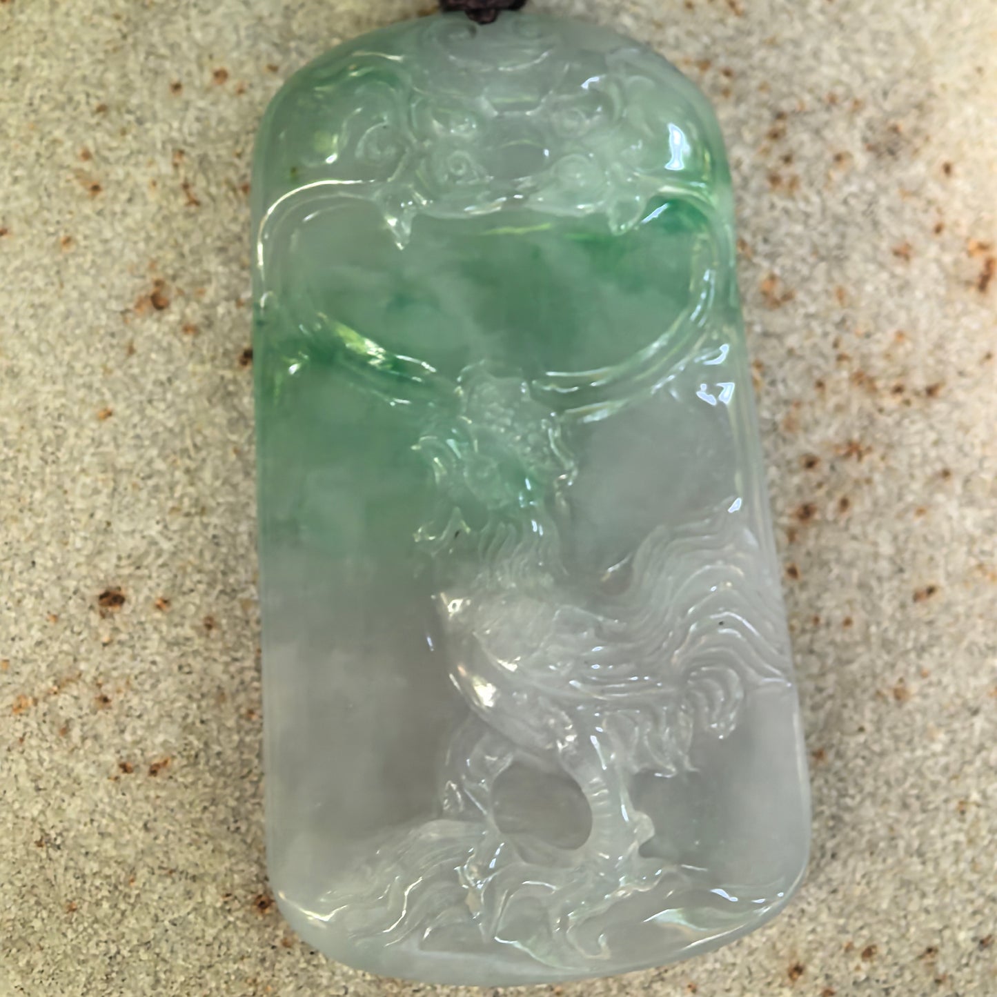 Front detail of the white-and-green jadeite plaque showing the rare rooster motif, cloud-like decoration, and carved feather details.