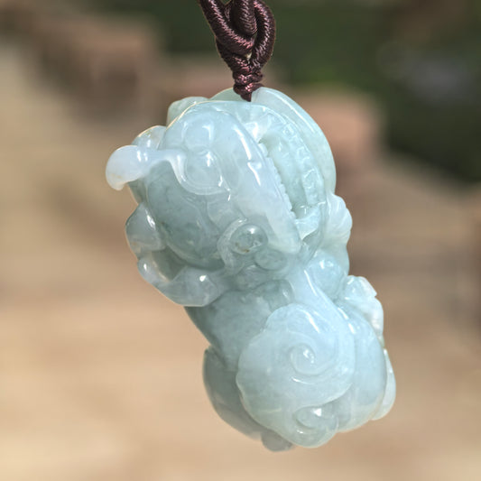 Natural Grade-A glutinous blue-green Pixiu jadeite pendant hanging from its cord and showing its substantial three-dimensional carving.