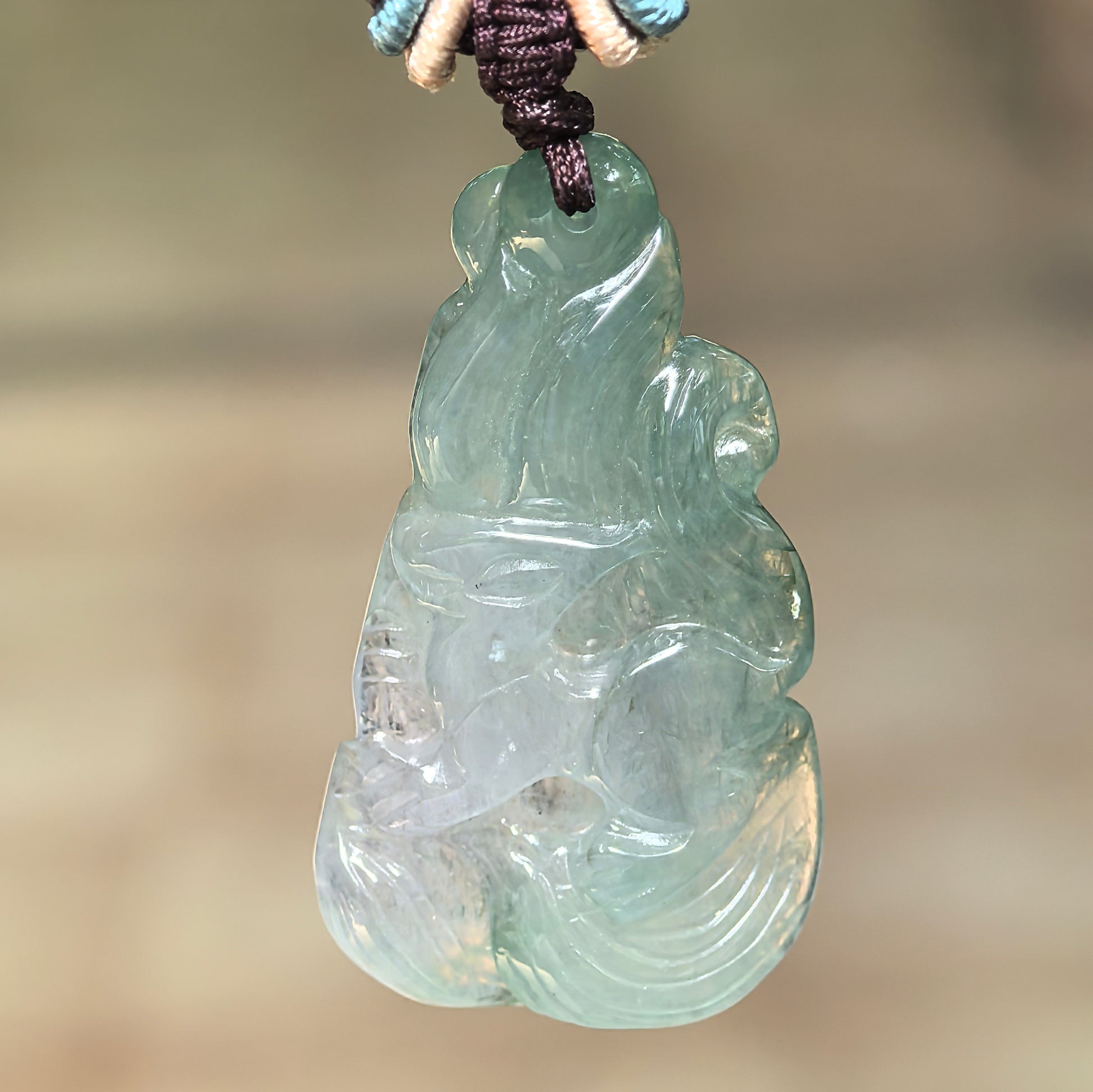 Natural Grade-A icy glutinous deep green nine-tailed fox jadeite pendant hanging from its decorative cord.