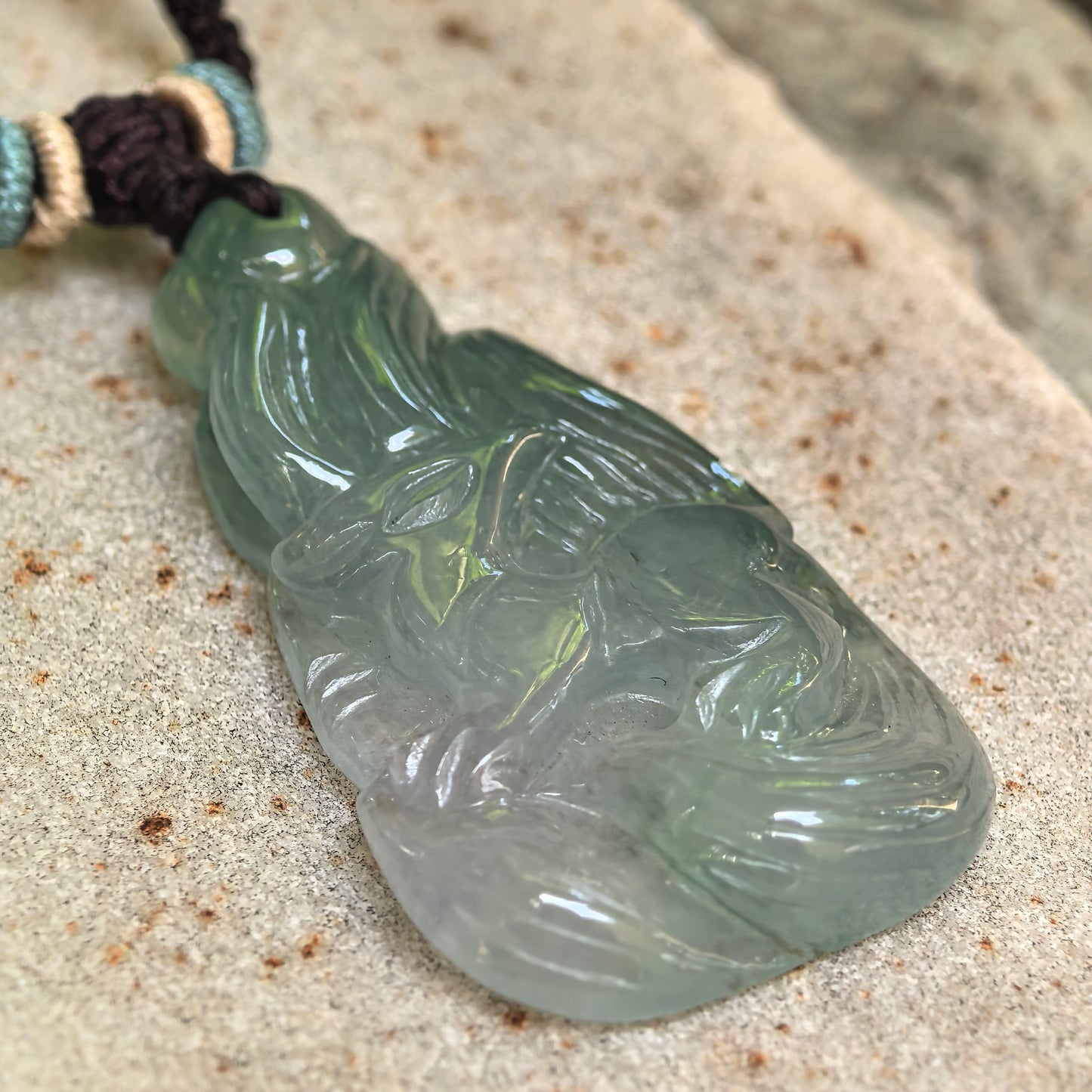 Close-up of the deep green nine-tailed fox jadeite pendant showing the carved face and layered flowing tails.
