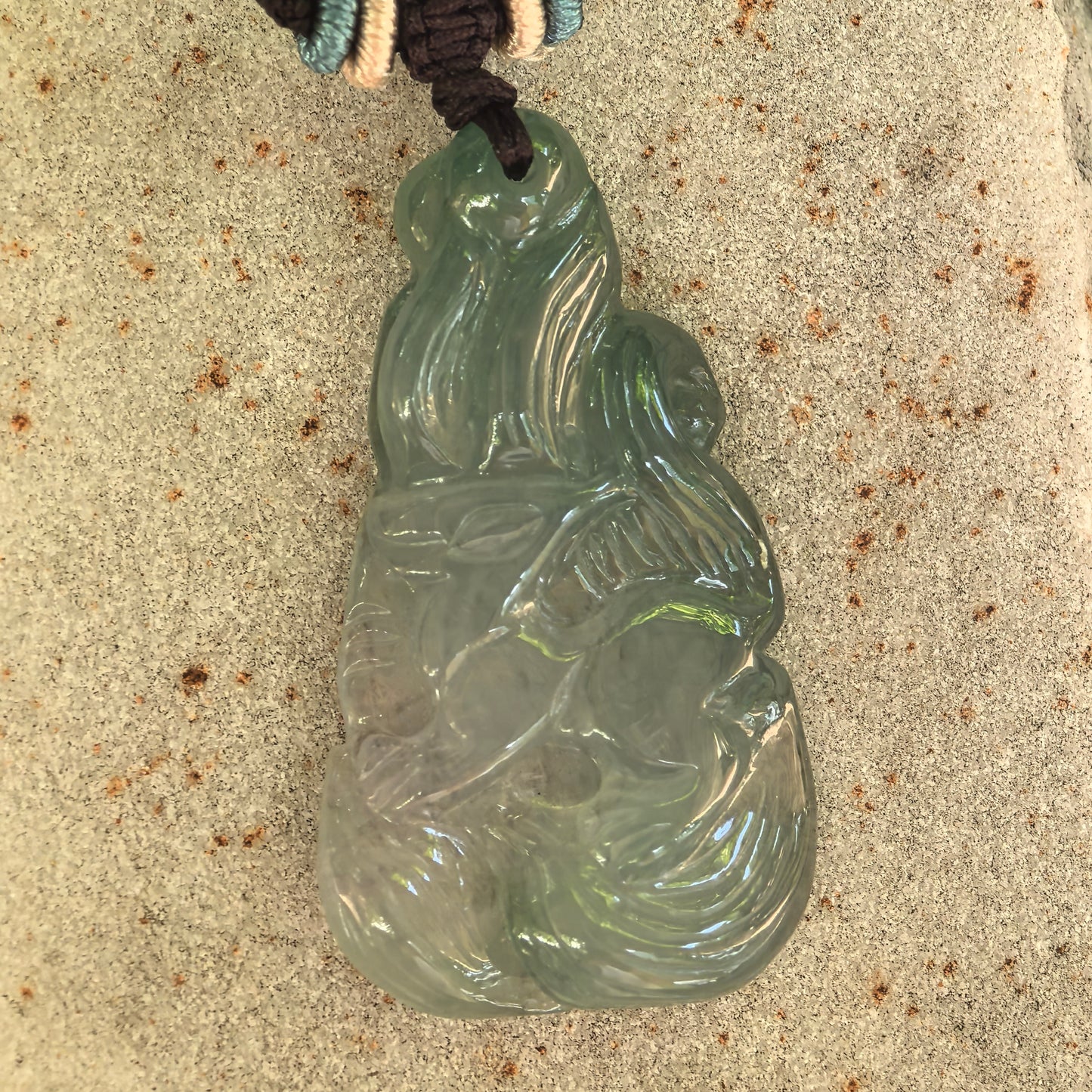 Detailed view of the icy glutinous jadeite fox pendant showing its polished surface, relief craftsmanship, and natural internal texture.