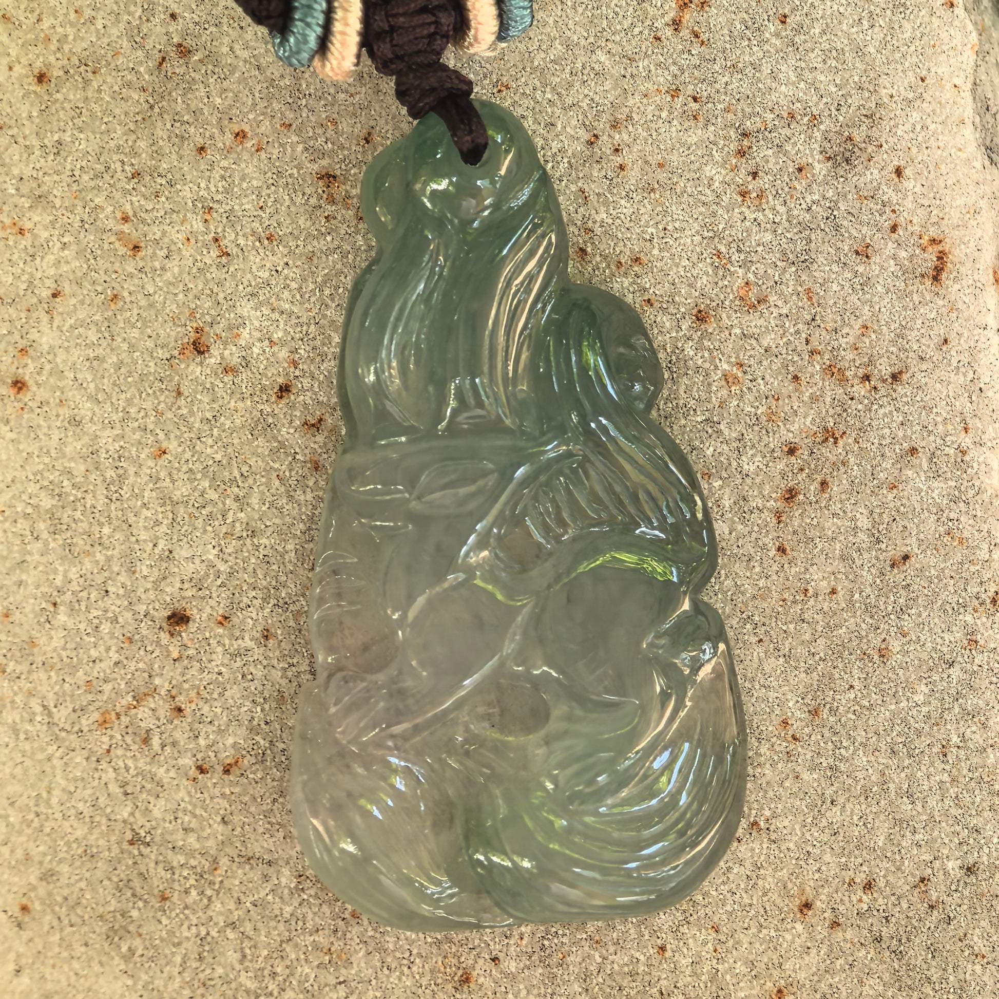 Detailed view of the icy glutinous jadeite fox pendant showing its polished surface, relief craftsmanship, and natural internal texture.