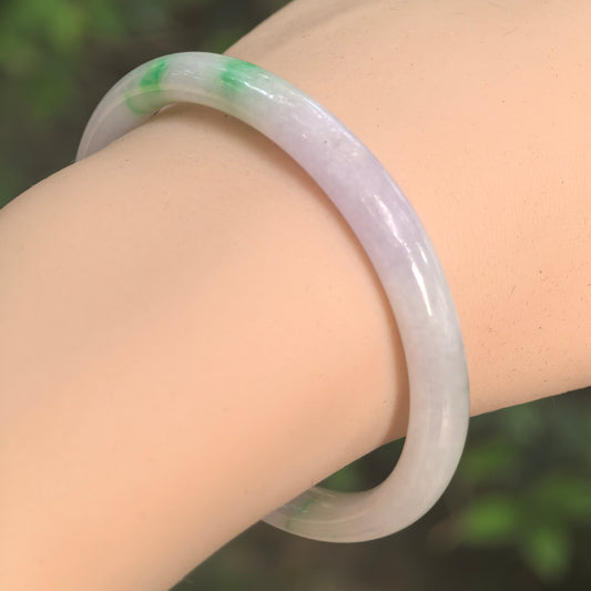 Natural Grade-A glutinous pale lavender and green oval jadeite bangle worn on the wrist.