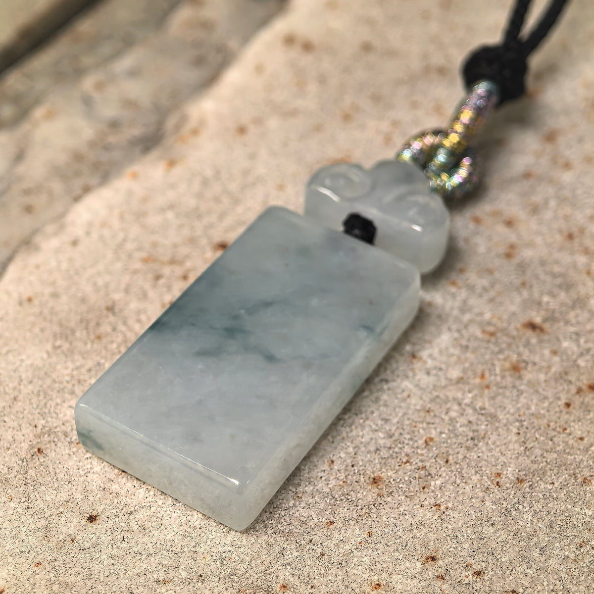 Angled close-up of the icy glutinous jadeite plaque showing its polished surface, thickness, and natural blue-green patterning.