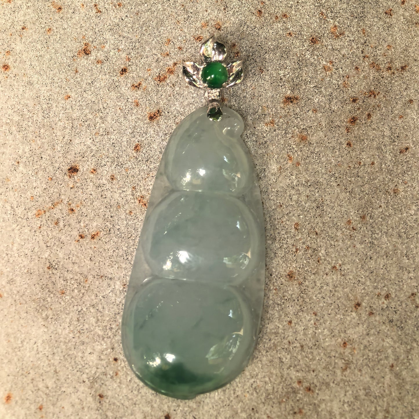 Front detail of the light green jadeite bean pendant with an 18K gold bail and green jadeite accent.