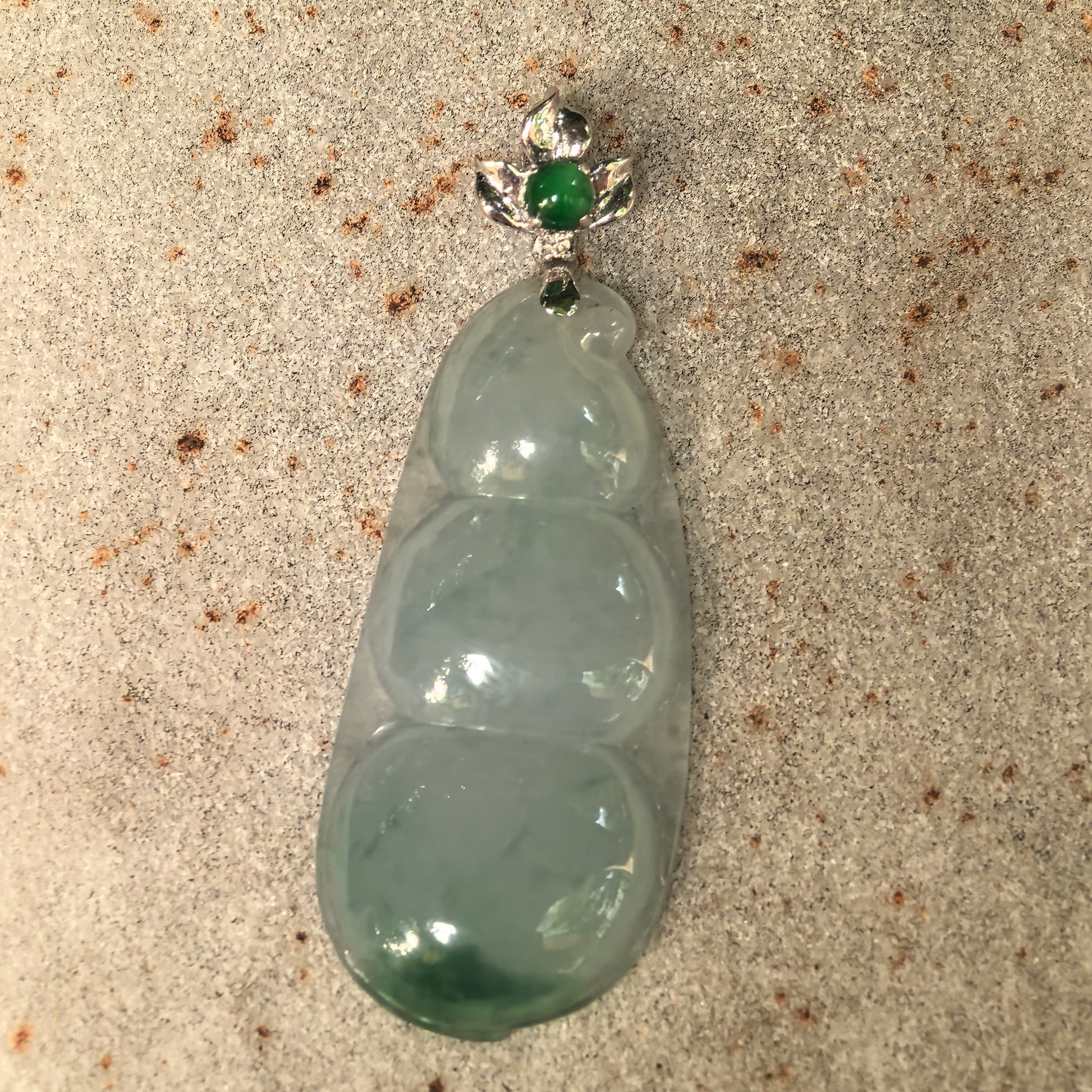 Front detail of the light green jadeite bean pendant with an 18K gold bail and green jadeite accent.