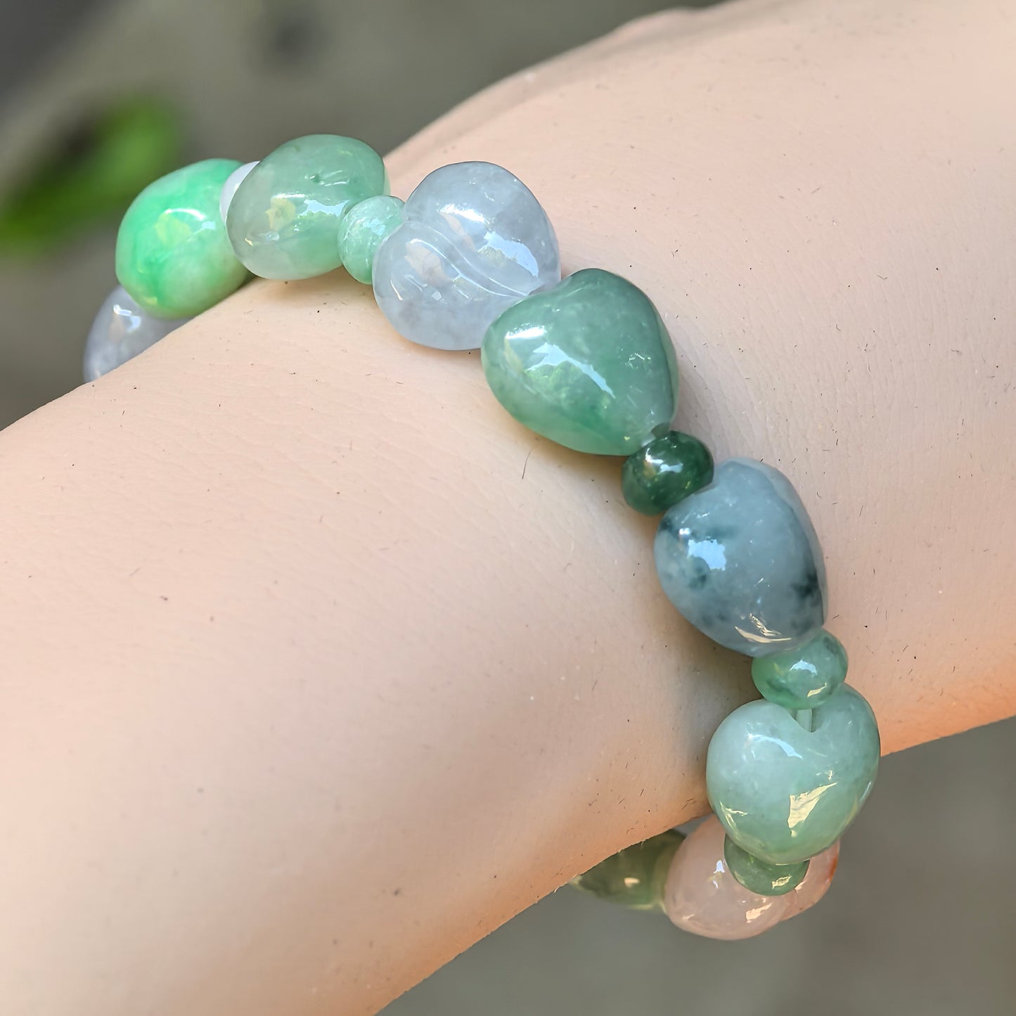 Wrist view of the multicolor Burmese jadeite bracelet showing peach-shaped beads and smaller spacer beads.
