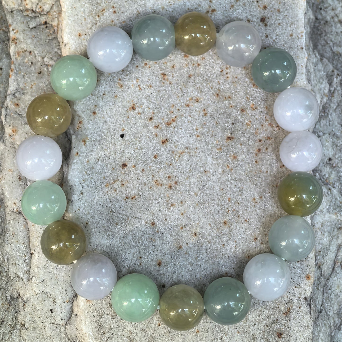 Top-down view of the icy glutinous jadeite bracelet showing all 19 polished round beads and natural color variation.