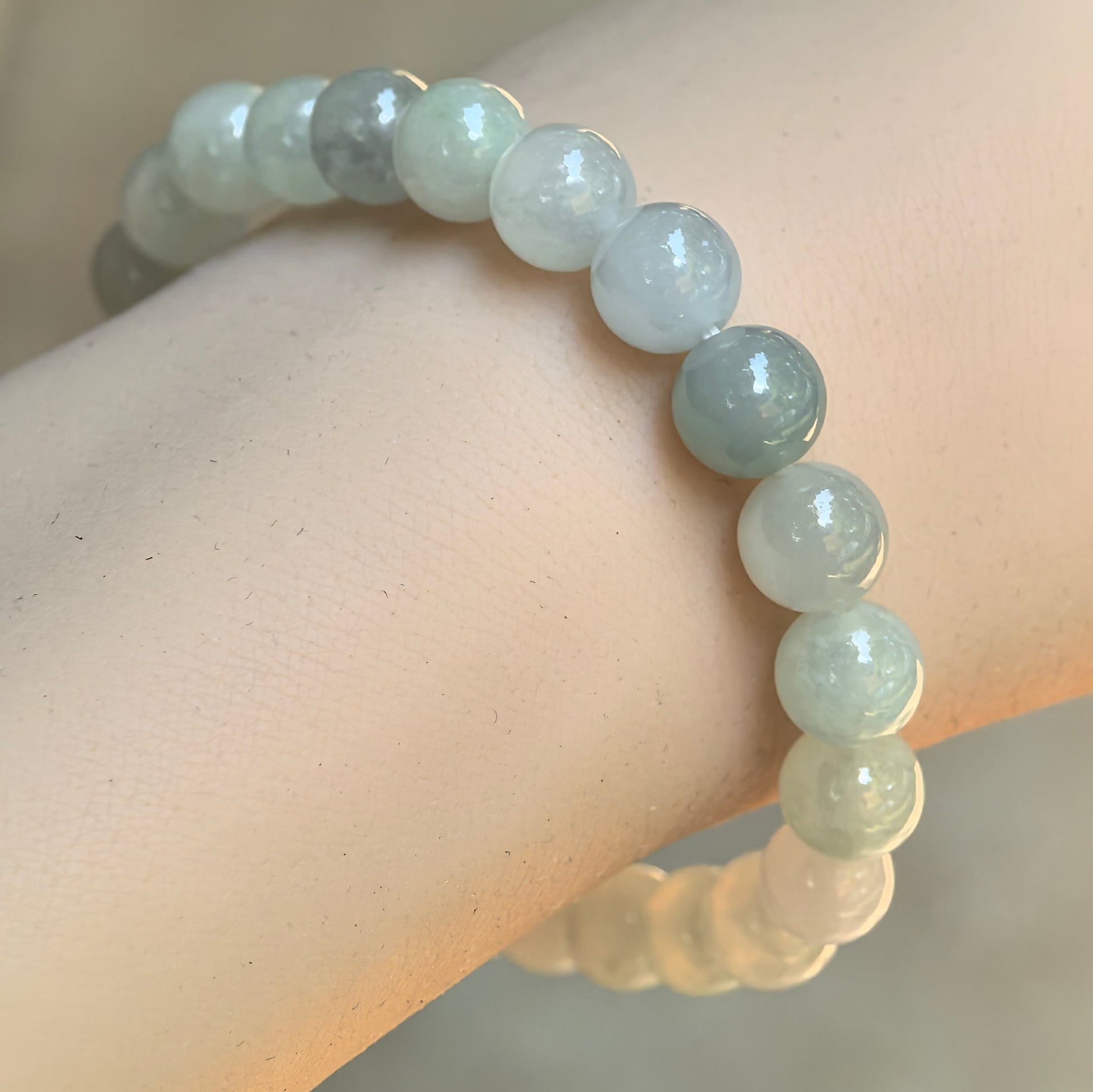 Close-up wearing view of a natural Grade-A icy glutinous light green jadeite bead bracelet with polished round beads.