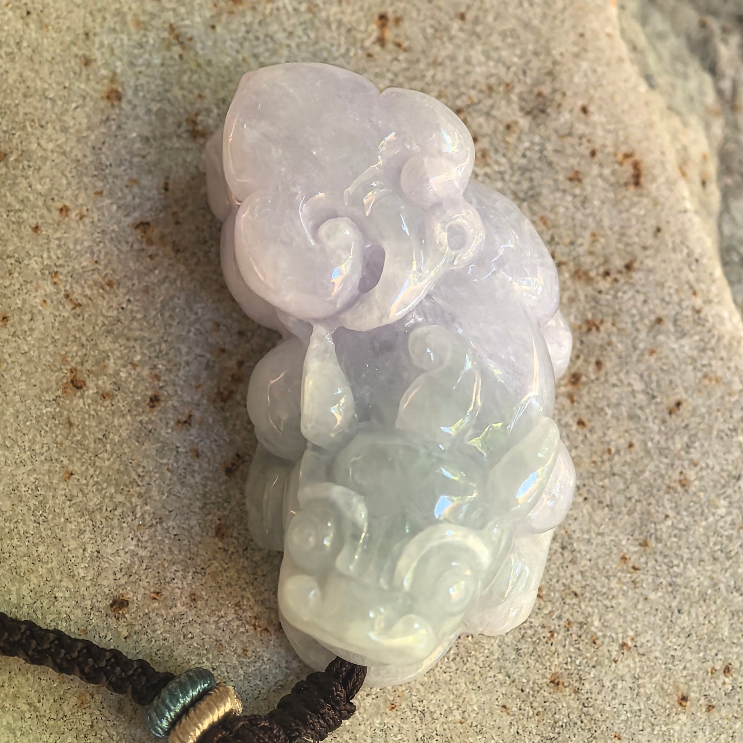 Detailed side view of the sculptural Pixiu jadeite pendant with raised cloud-like forms and glutinous texture.