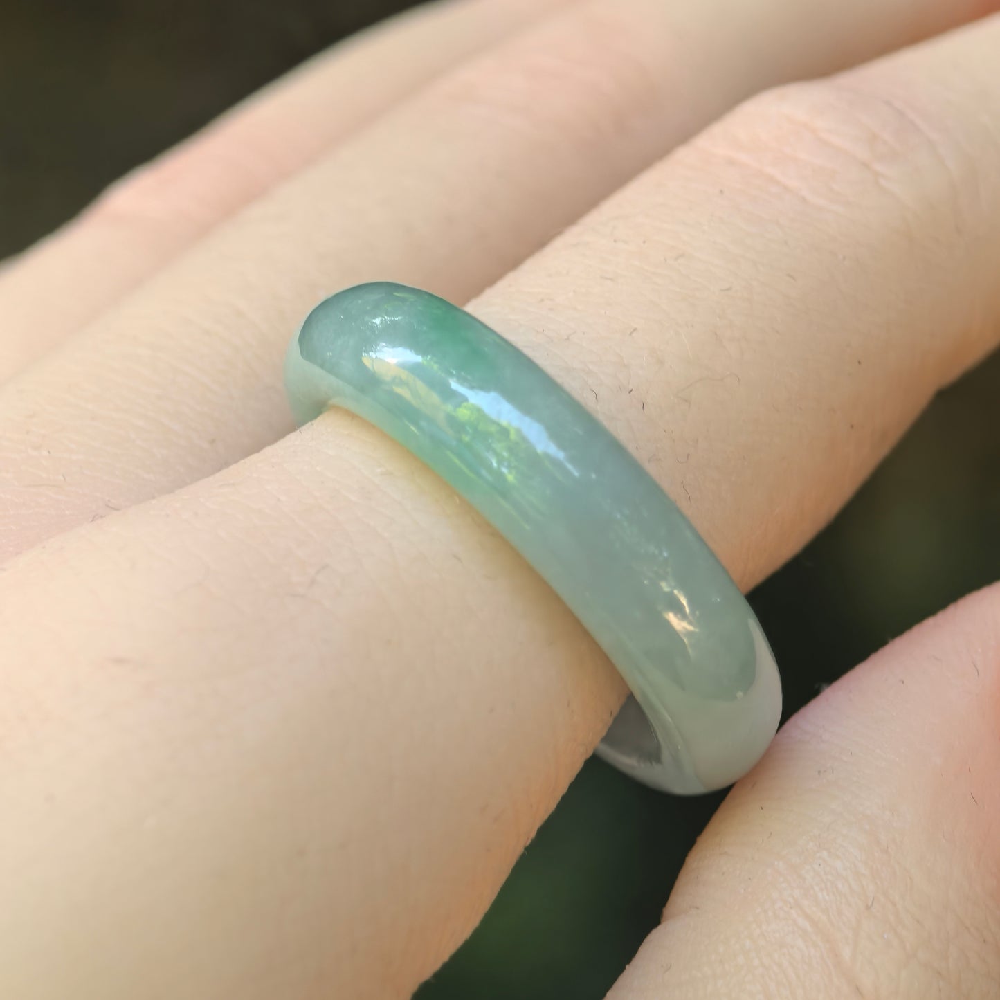 Natural Grade-A icy glutinous light green jadeite ring band worn on a finger in close-up view.