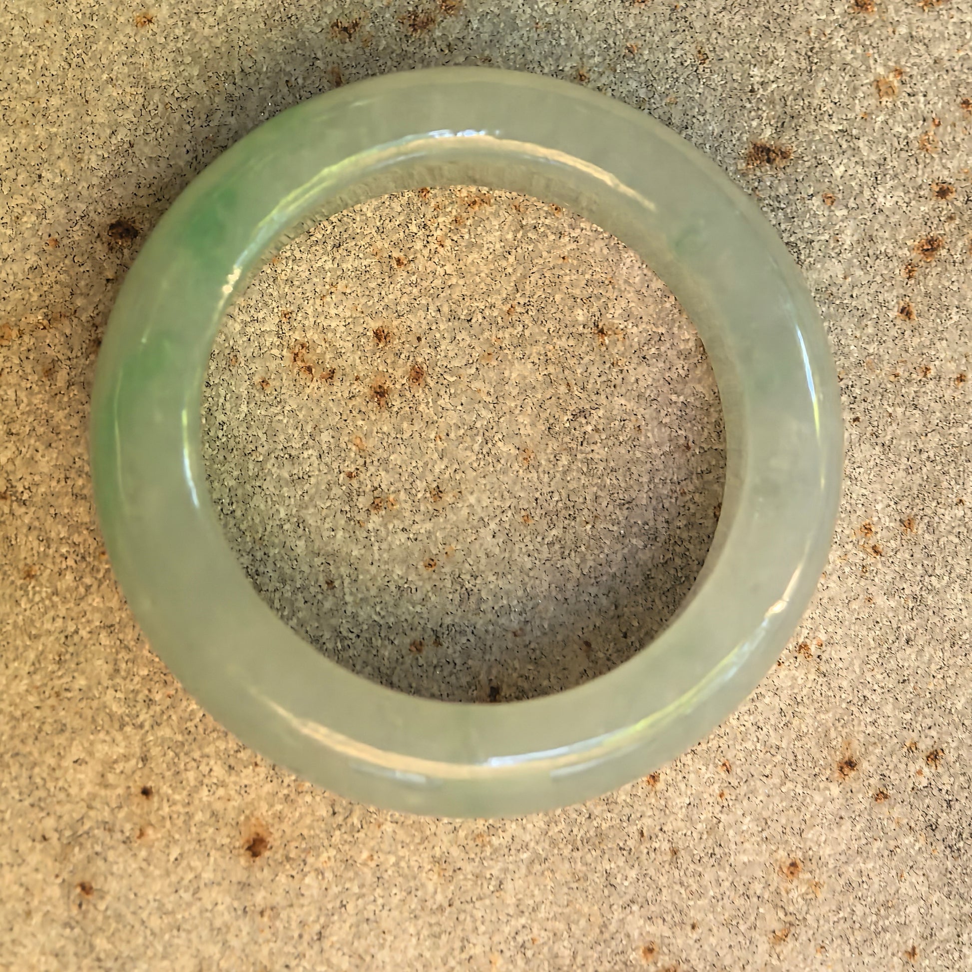 Top view of the circular jadeite ring band showing its light green color and even inner opening.