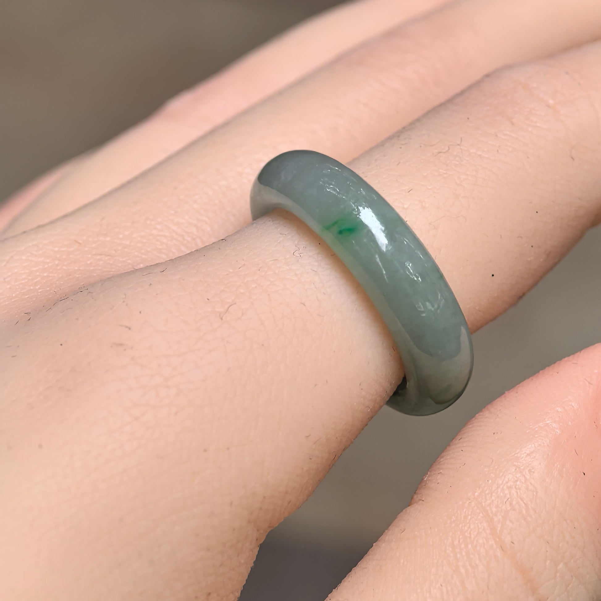 Natural Grade-A icy glutinous light green jadeite ring band worn on a finger, showing its rounded profile and smooth polished surface.