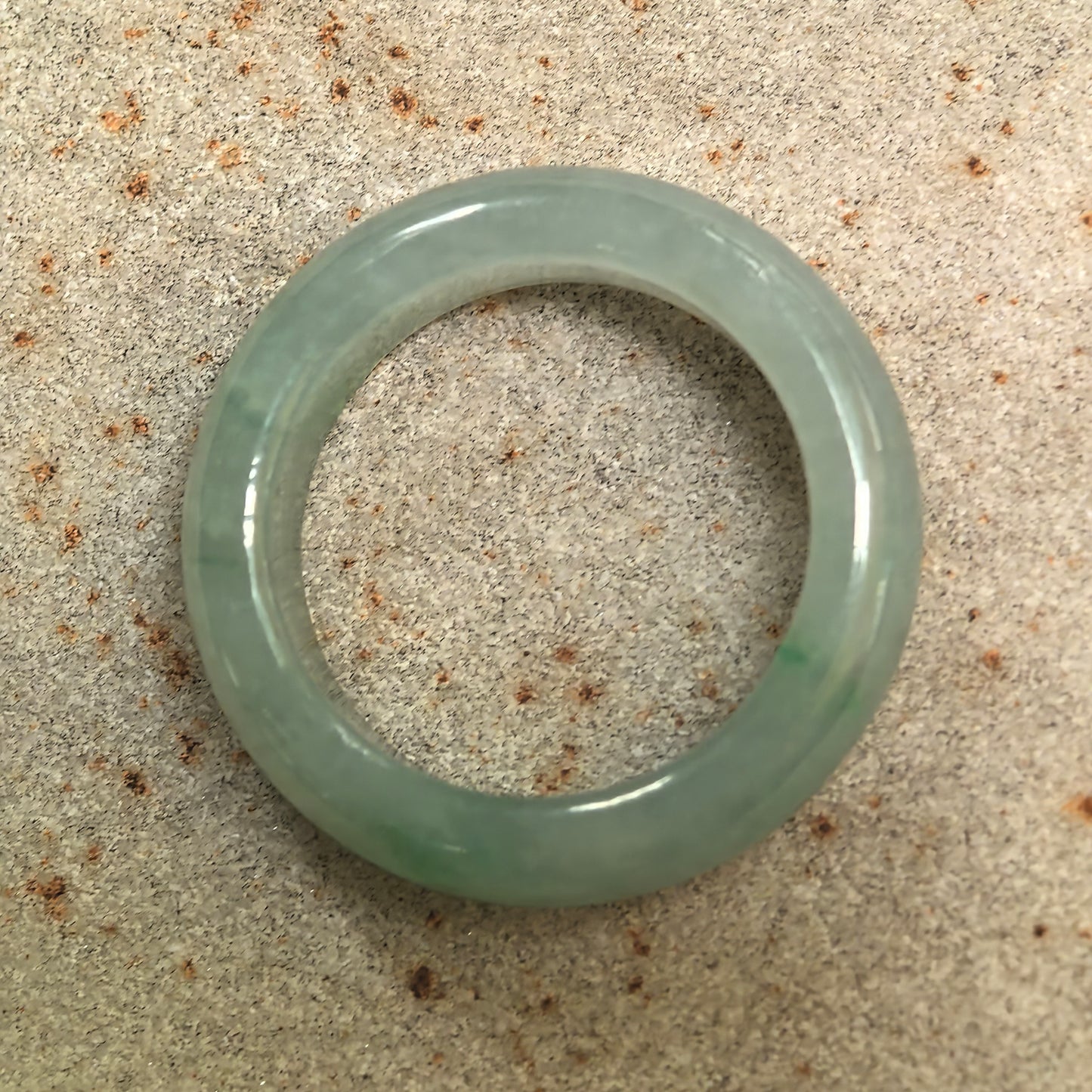 Top view of a round light green jadeite ring band with a complete circular structure and no visible flaws.