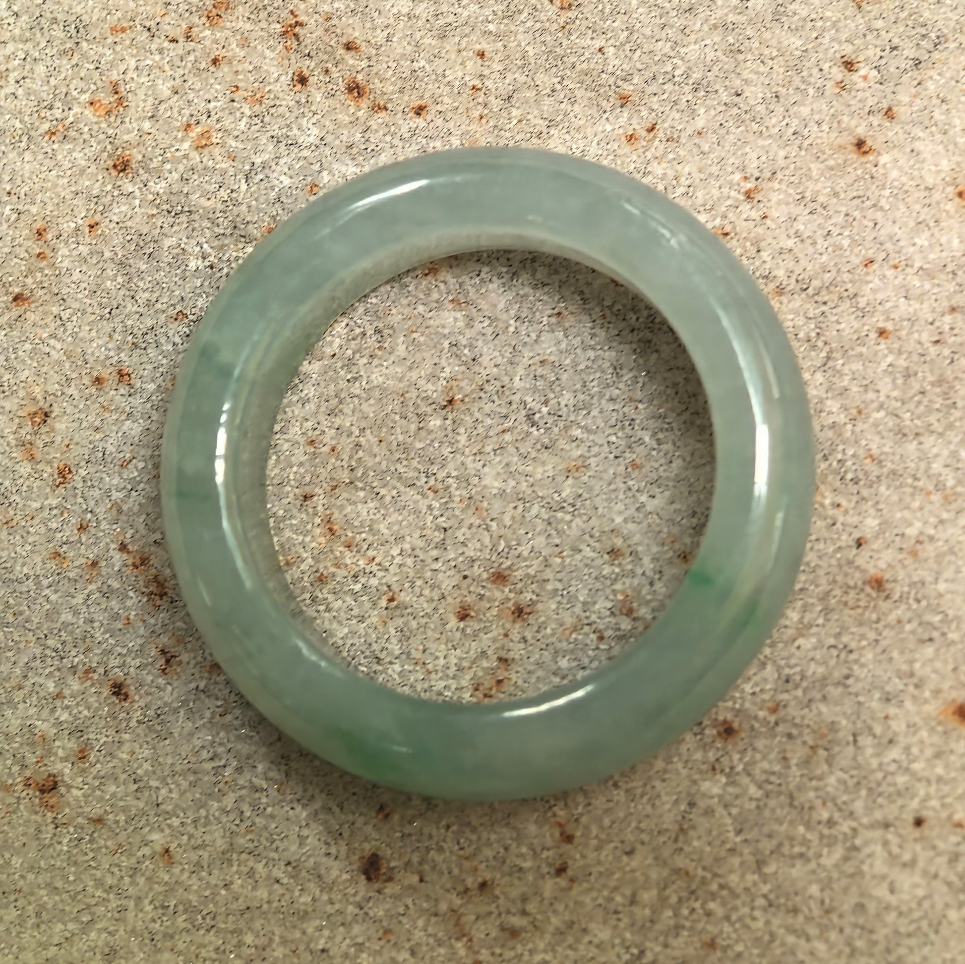 Top view of a round light green jadeite ring band with a complete circular structure and no visible flaws.