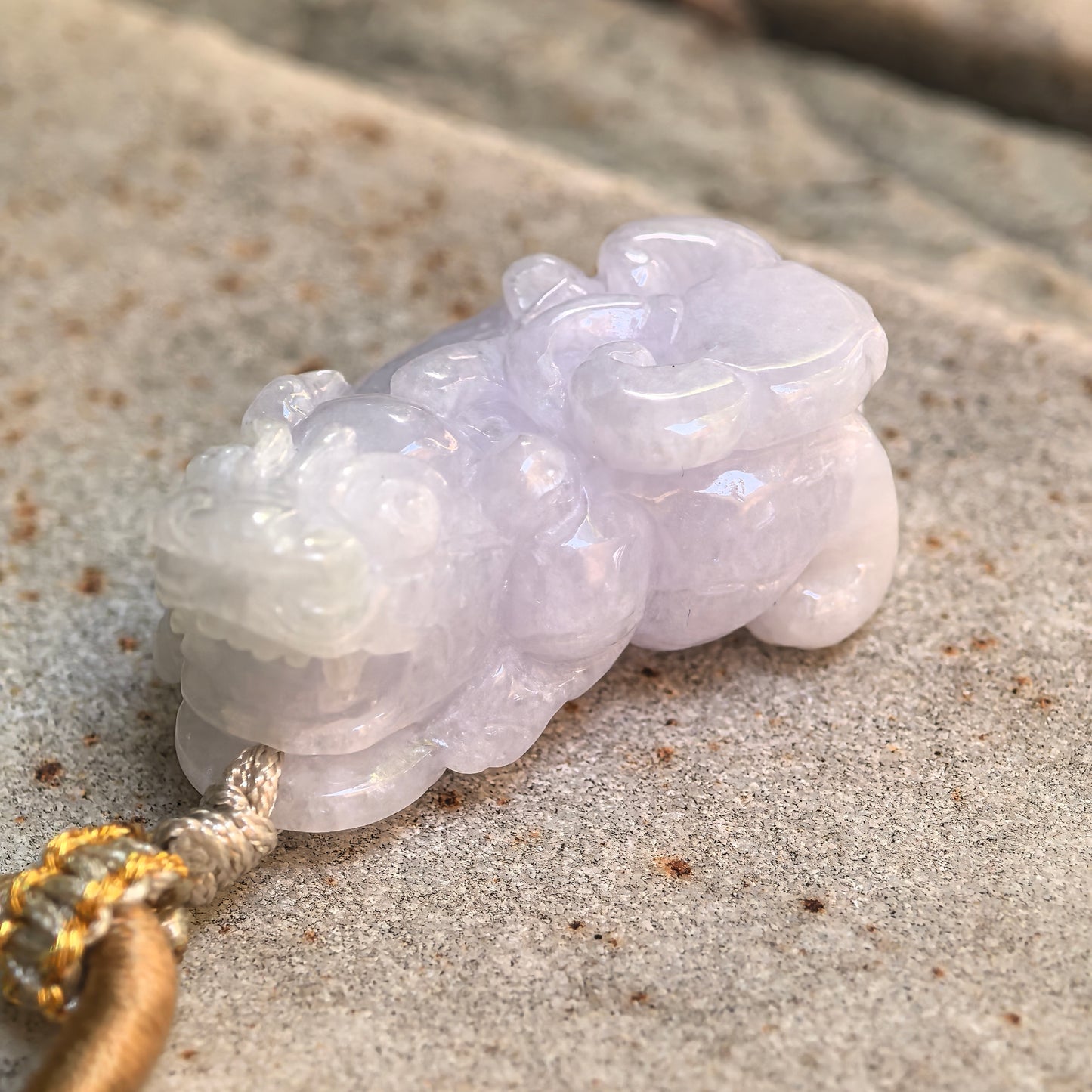 Angled close-up of a light spring Burmese jadeite Pixiu pendant showing its rounded body and detailed craftsmanship.