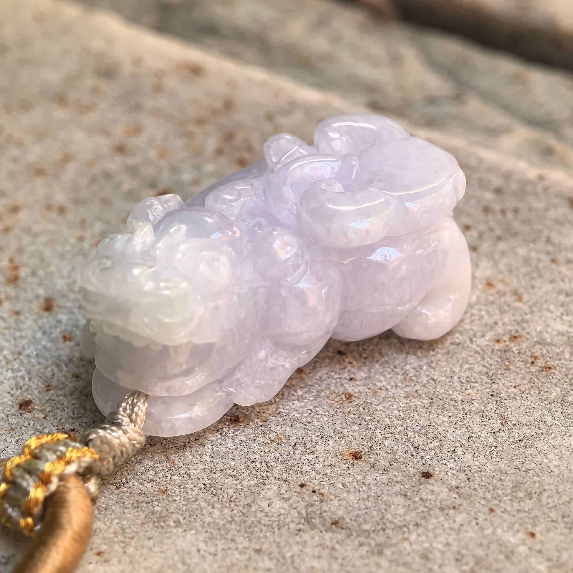 Angled close-up of a light spring Burmese jadeite Pixiu pendant showing its rounded body and detailed craftsmanship.