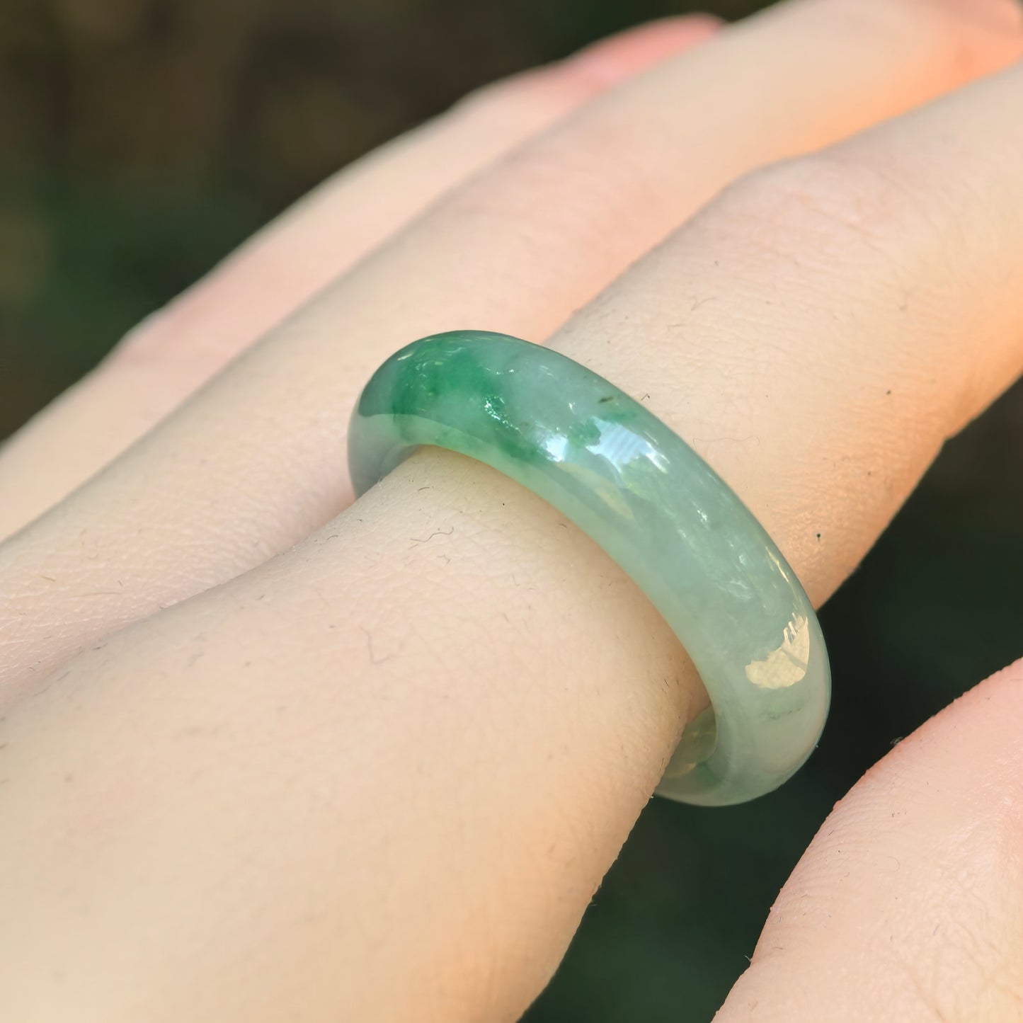 Natural Grade-A icy glutinous light green jadeite ring band shown on a finger with a deeper green accent.